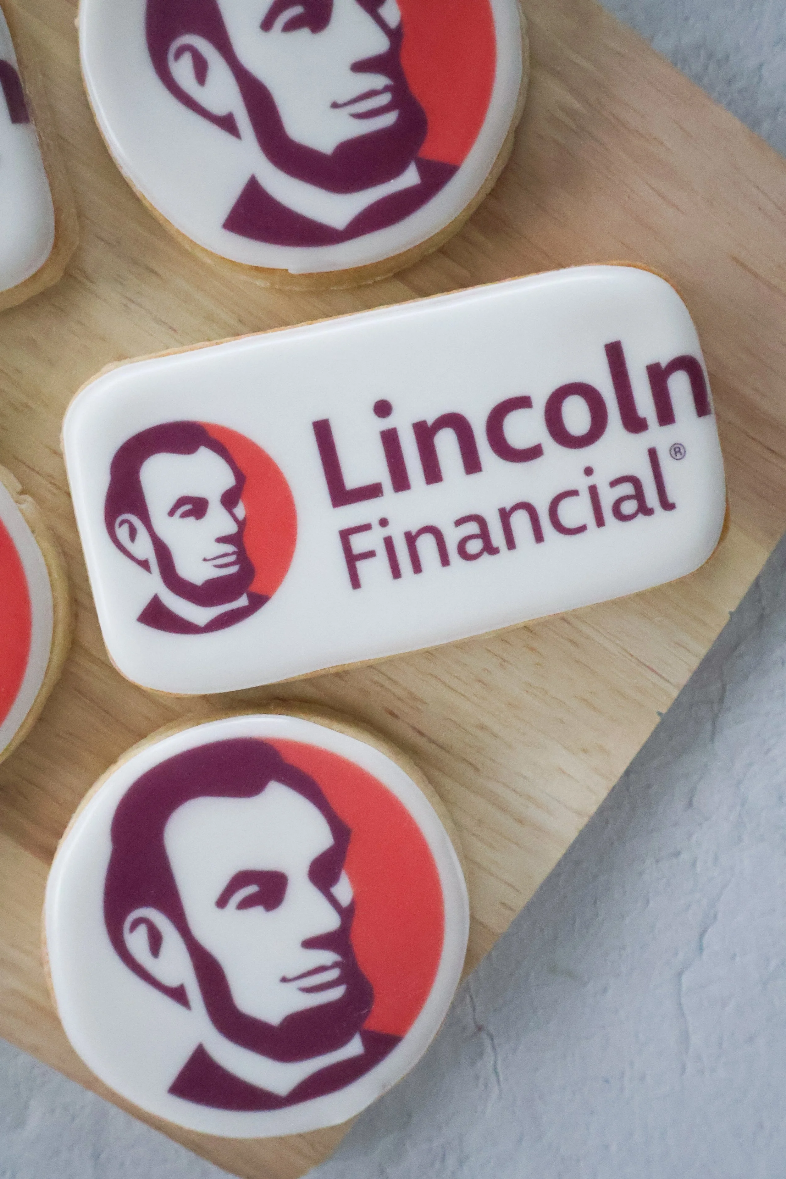 Cookies with KFC logo and Lincoln Financial Group logo on them, placed on a wooden surface.