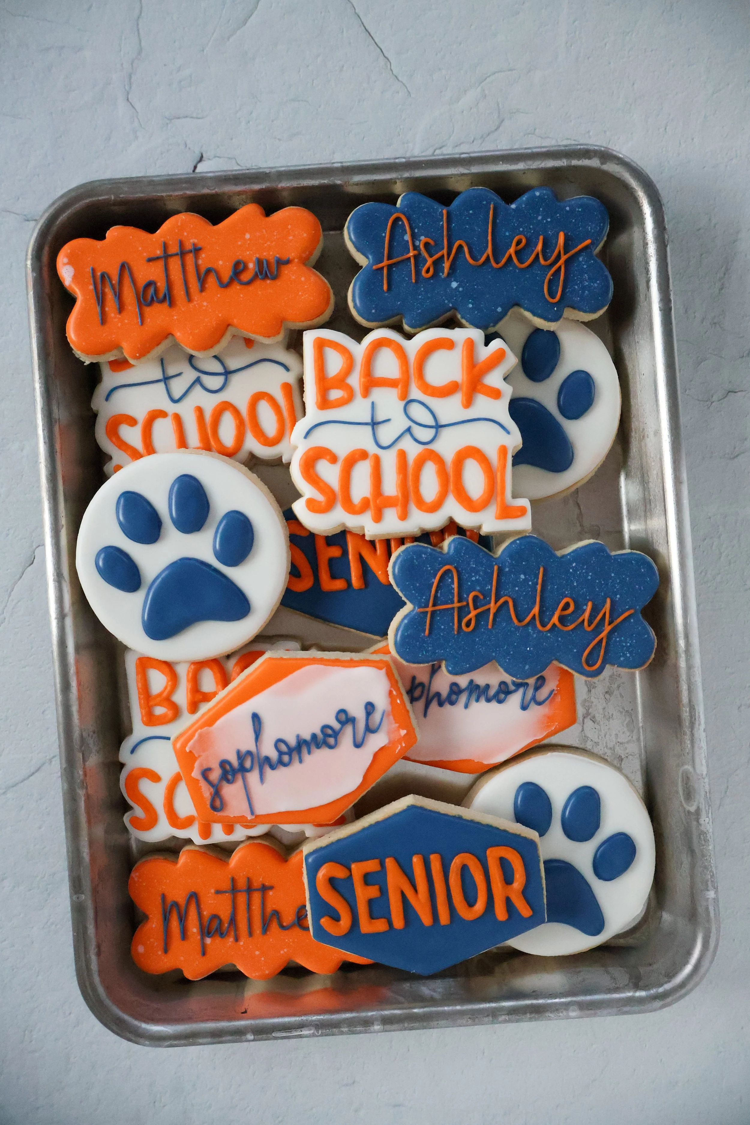 Decorative cookies with school-related messages and designs, including names 'Matthew' and 'Ashley', and phrases like 'Back to School' and 'Senior'.