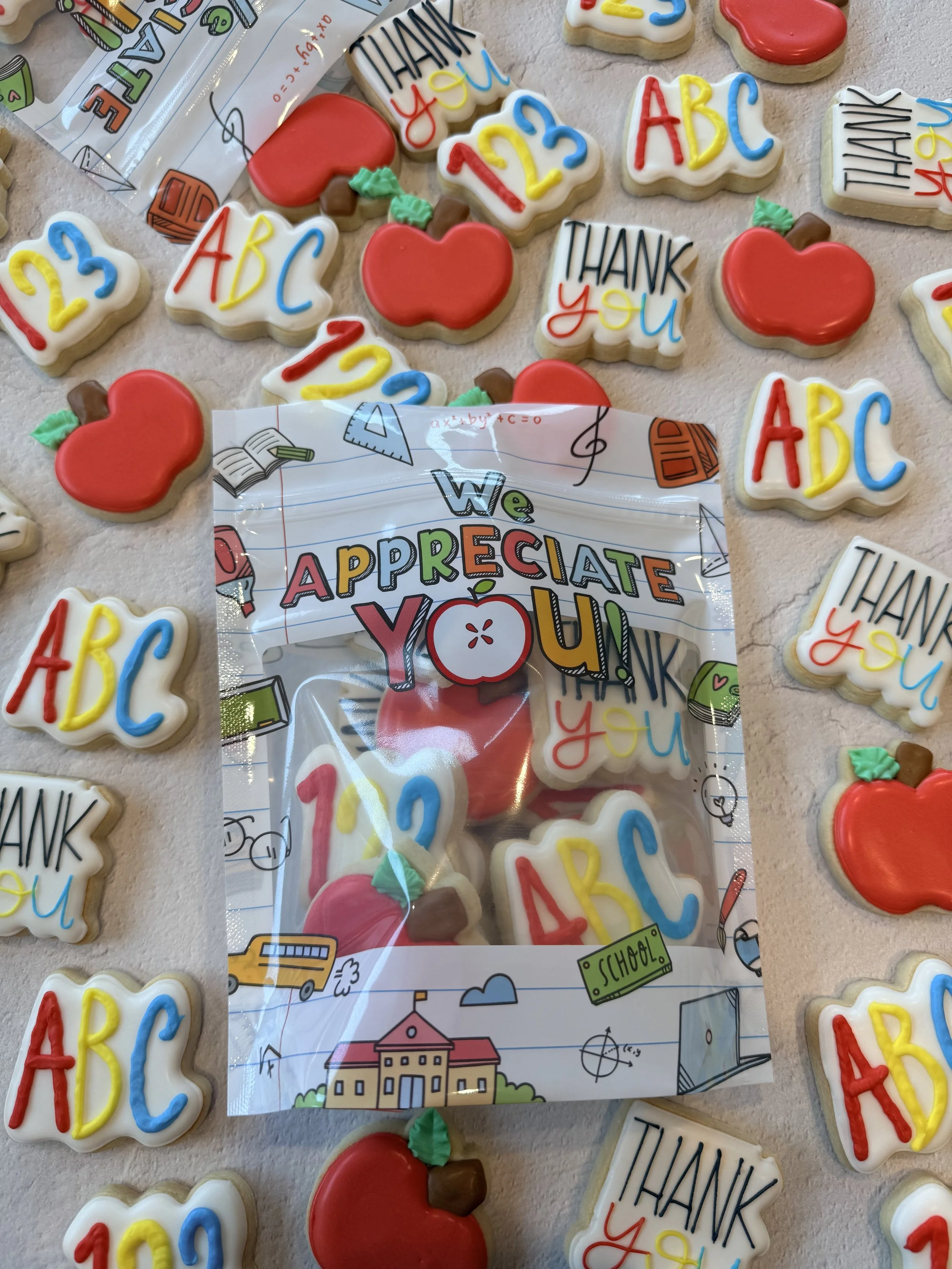 A colorful assortment of decorated cookies with school-themed and alphabet designs, including cookies with 'Thank You' messages, ABC, 123, apples, and school-related doodles.