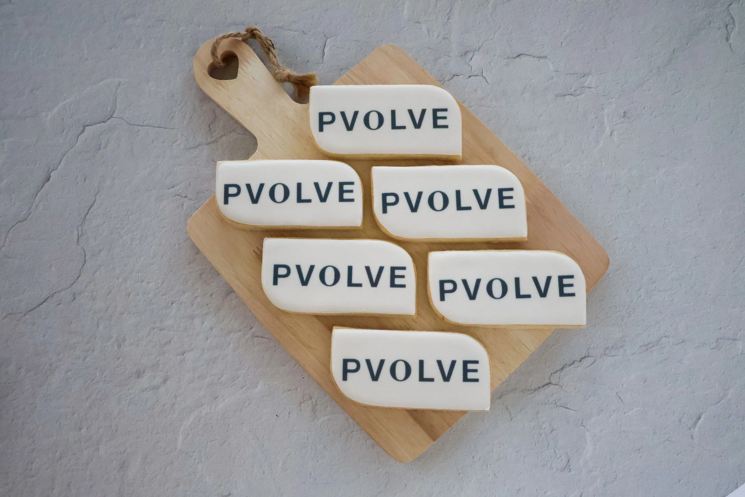 Wooden board with six mini soap bars, each labeled 'PVOLVE' in black letters, arranged in two columns on a textured gray surface.