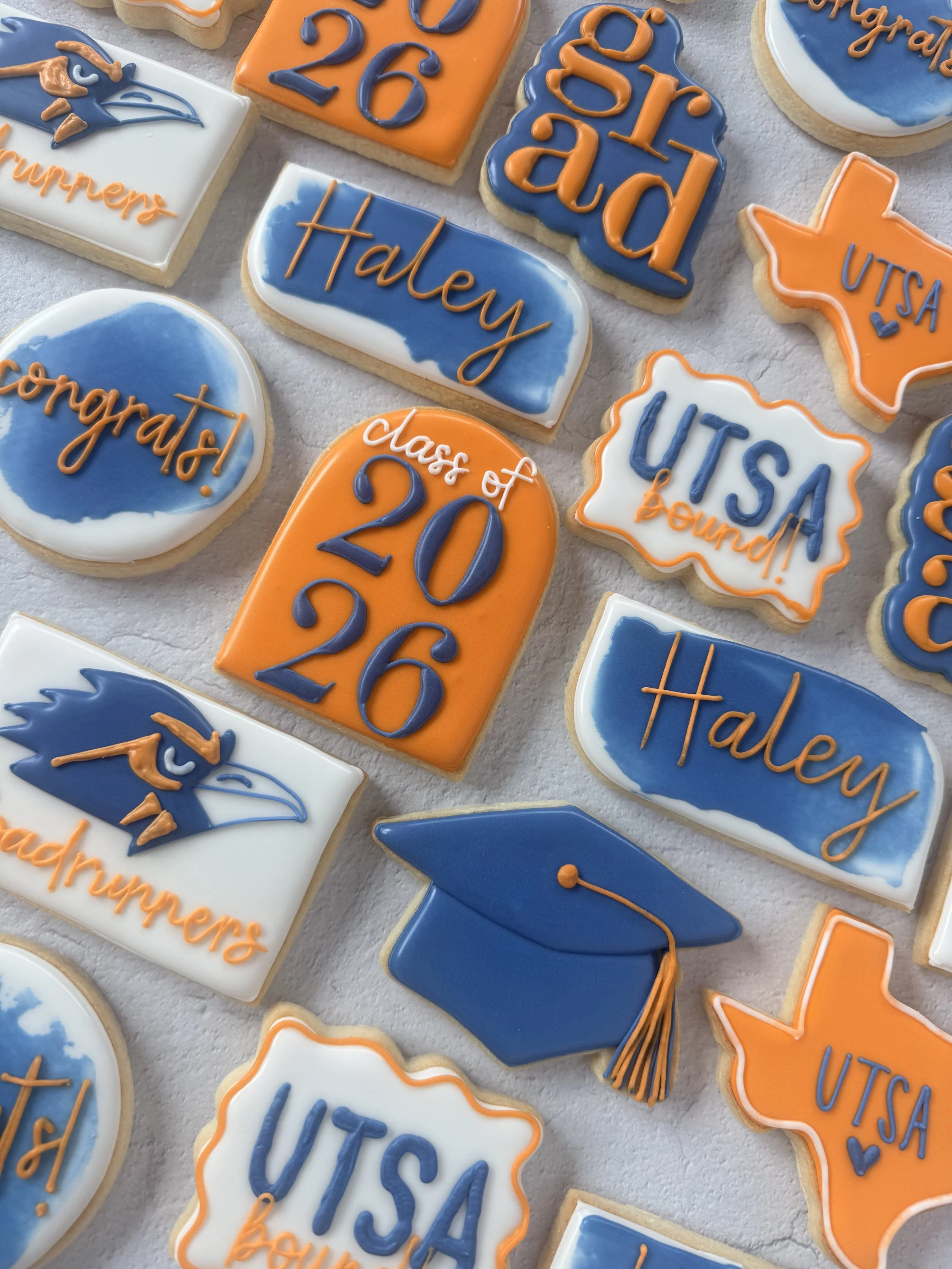 Decorated cookies celebrating the U.S. UTA class of 2026, with phrases like 'congrats!', 'class of 2026', 'Hale', and 'UTSA', featuring mascot images, graduation caps, and vibrant colors.