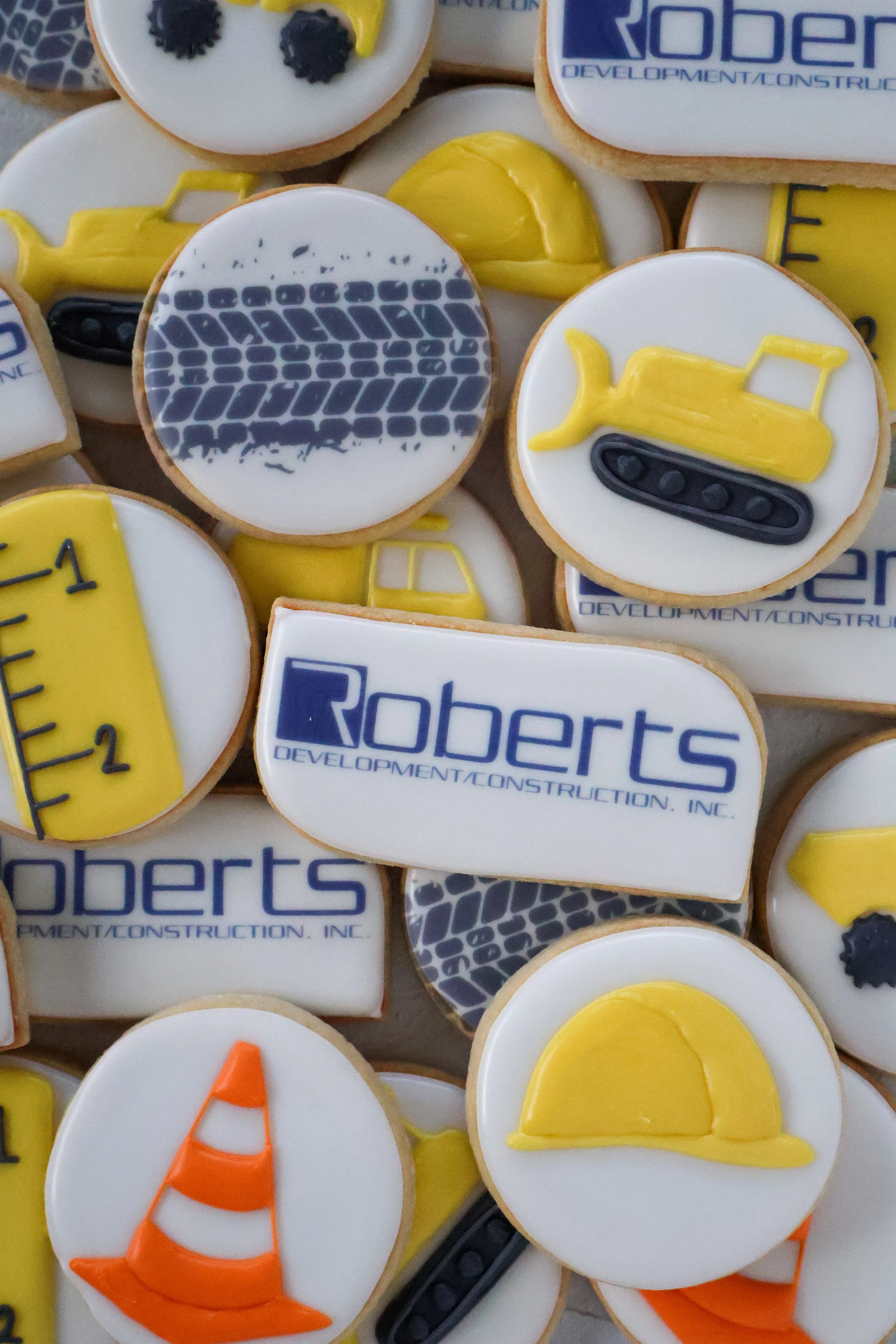 Decorative cookies themed with construction equipment, including yellow bulldozers, construction cones, safety vests, and the Roberts Development sign.