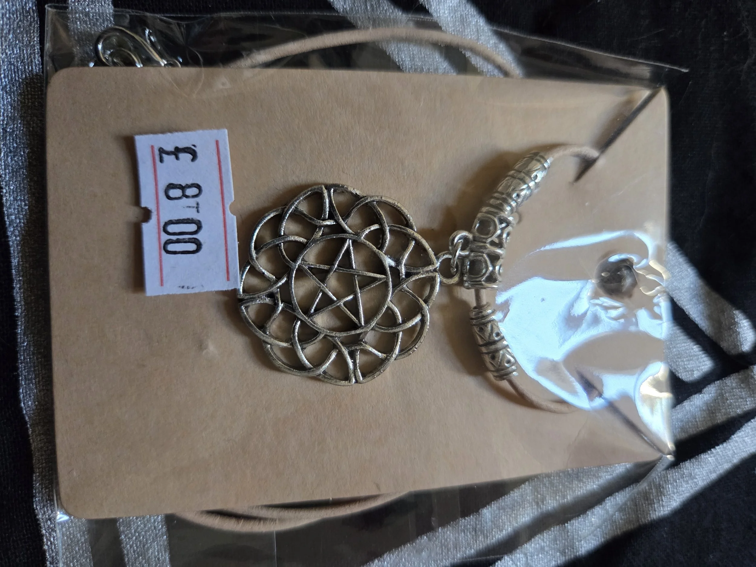 Round charm with beige leather cord