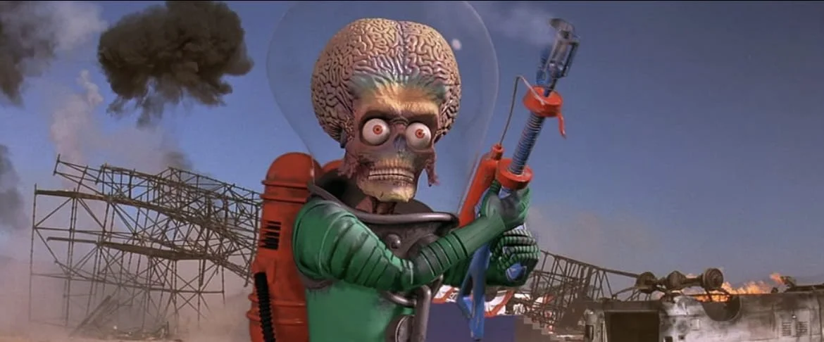 A cartoon character with a human brain for a head, wearing a spacesuit and holding a futuristic weapon, standing amidst a destroyed landscape with smoke and debris.