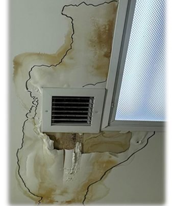 Ceiling with water damage and stained patches around an air vent and a window.