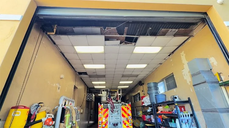 Fire department truck inside a garage with the ceiling partially collapsed.