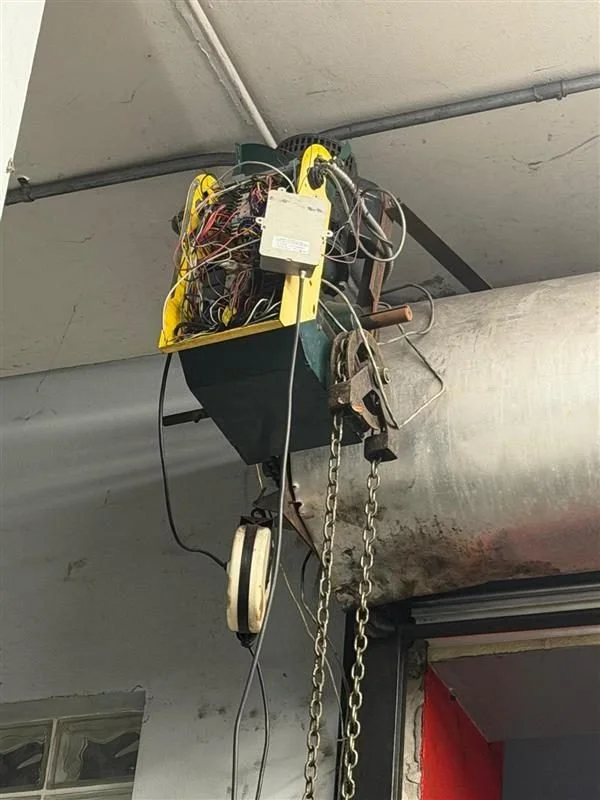 Close-up of a garage door opener with exposed wiring and mechanisms hanging from the ceiling.