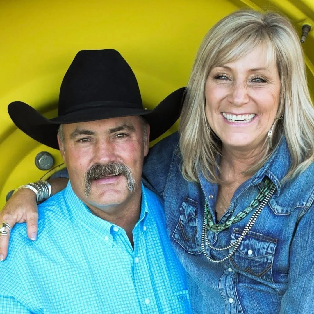 Two smiling people, a man with a cowboy hat and a woman with blonde hair, posing together in front of a yellow background.