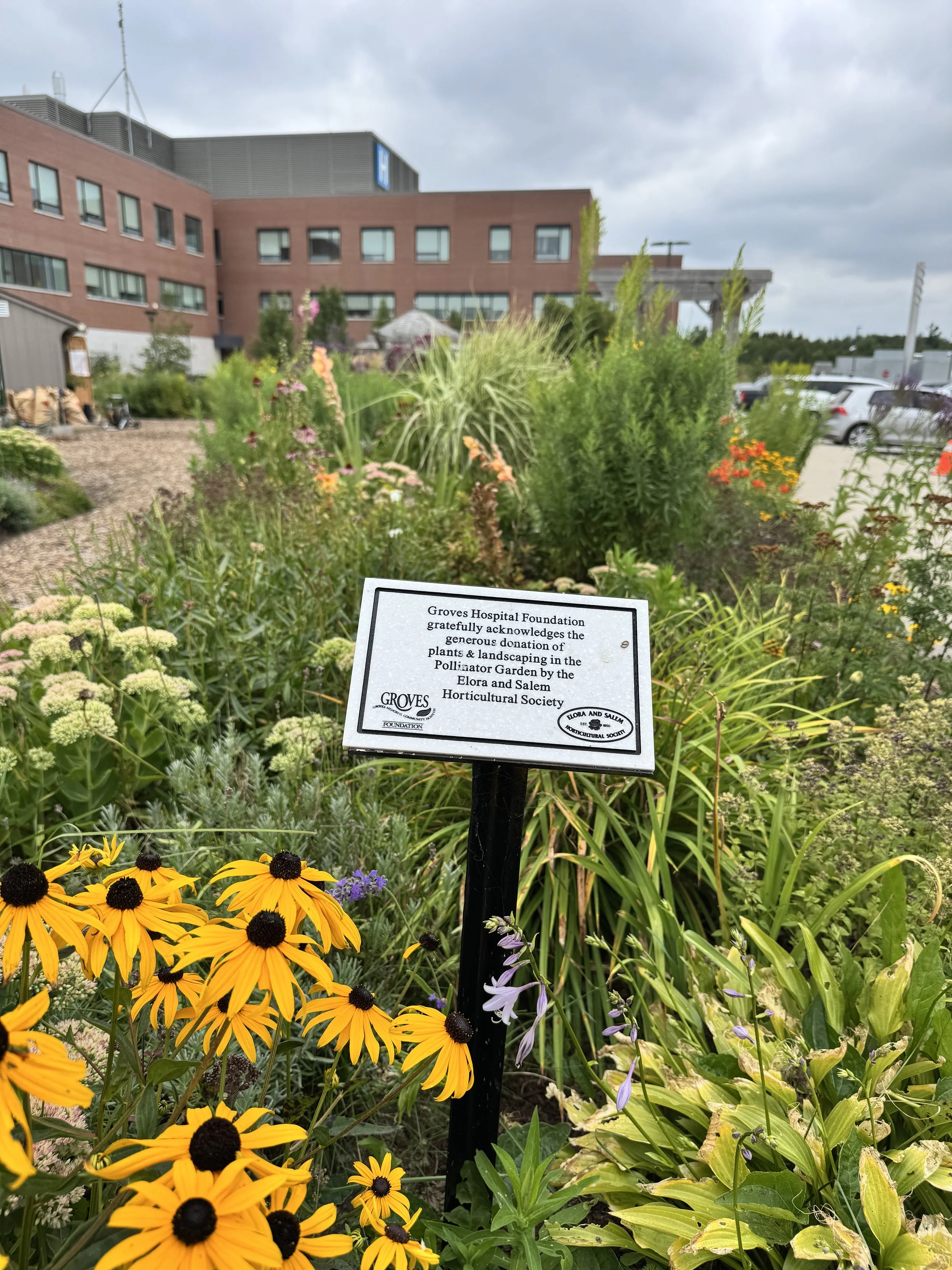 Photo of a sign in front of gardens and a pathway