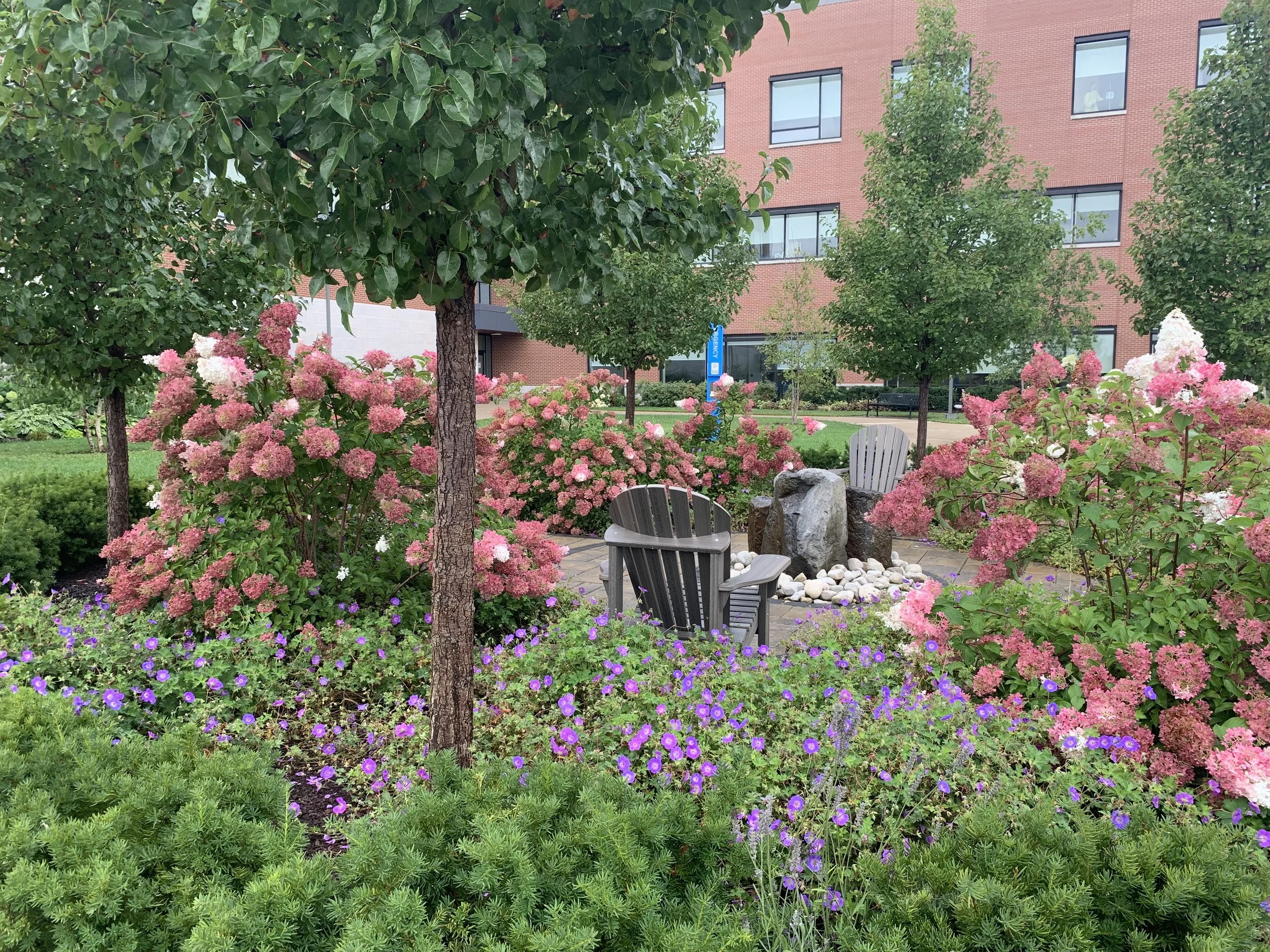Photo of gardens surrounding chairs and a water fountain in the middle
