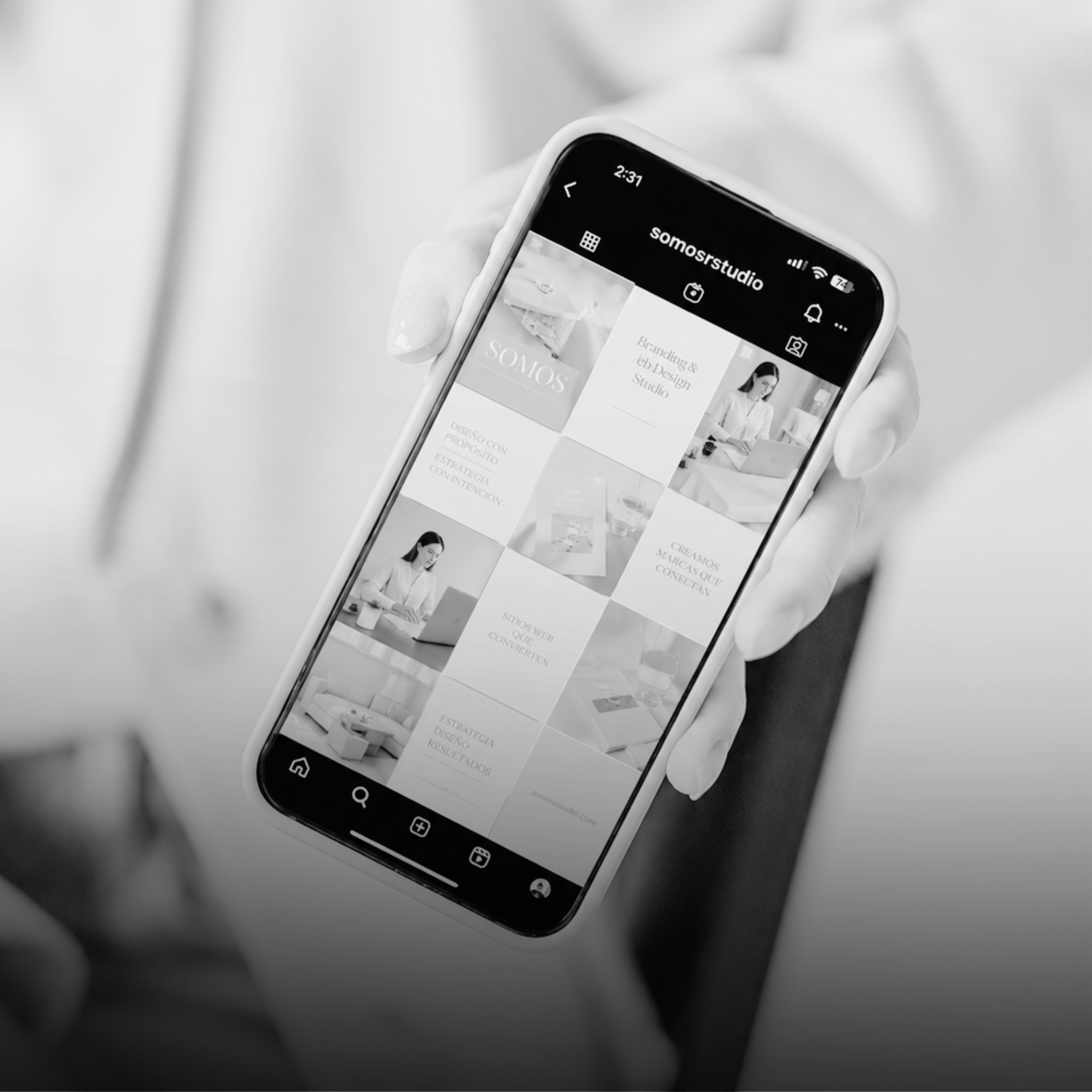 A smartphone displaying a website or app with a grid layout, showing various images and text, held in a person's hand.