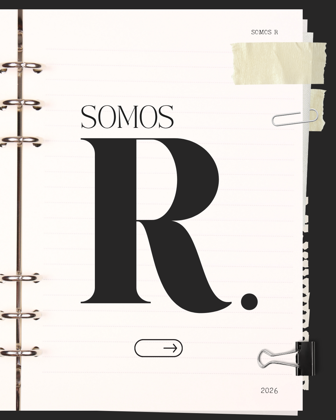 A notebook page with the words 'SOMOS R' and a large letter 'R.' in black font, held in a binder with a black background, paper clips, and tape.