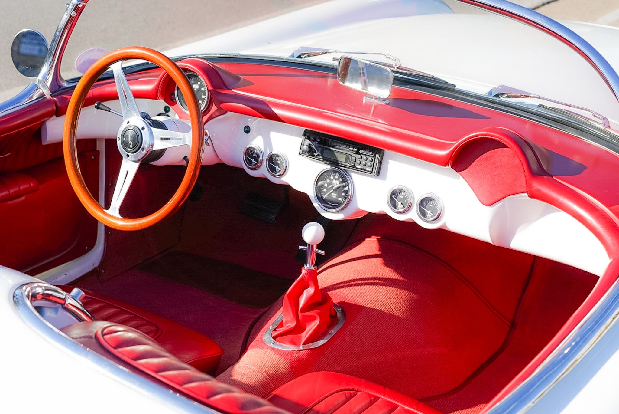 Red interior of a vintage convertible car, showing the steering wheel, dashboard, and front seats