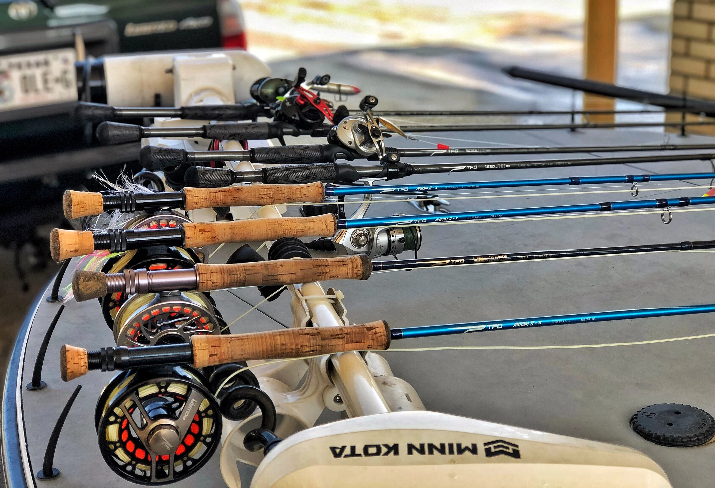 Multiple fishing rods with cork handles and reels, laid out on a boat's surface.