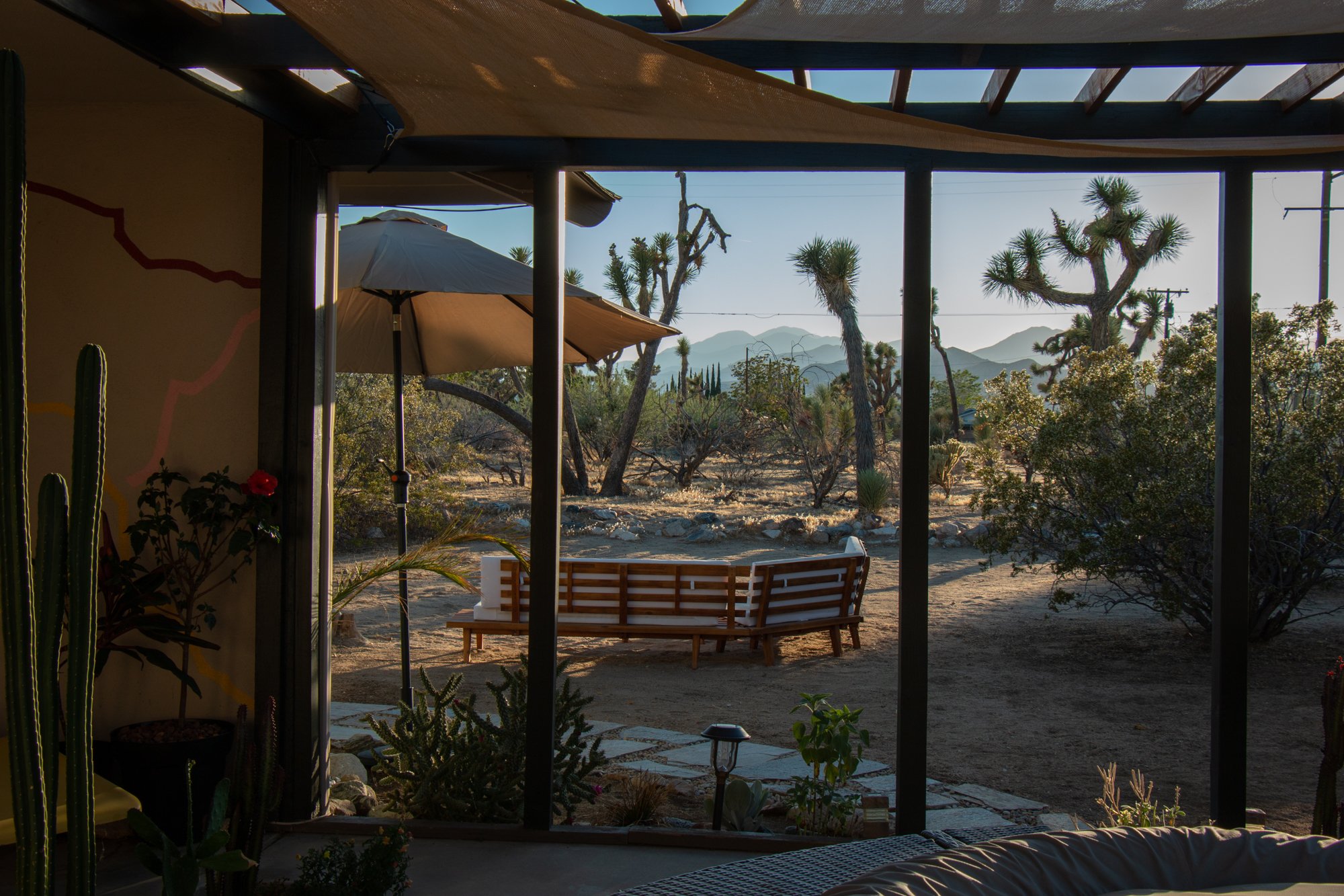 A backyard view through an open patio with desert trees and mountains in the background during daytime.