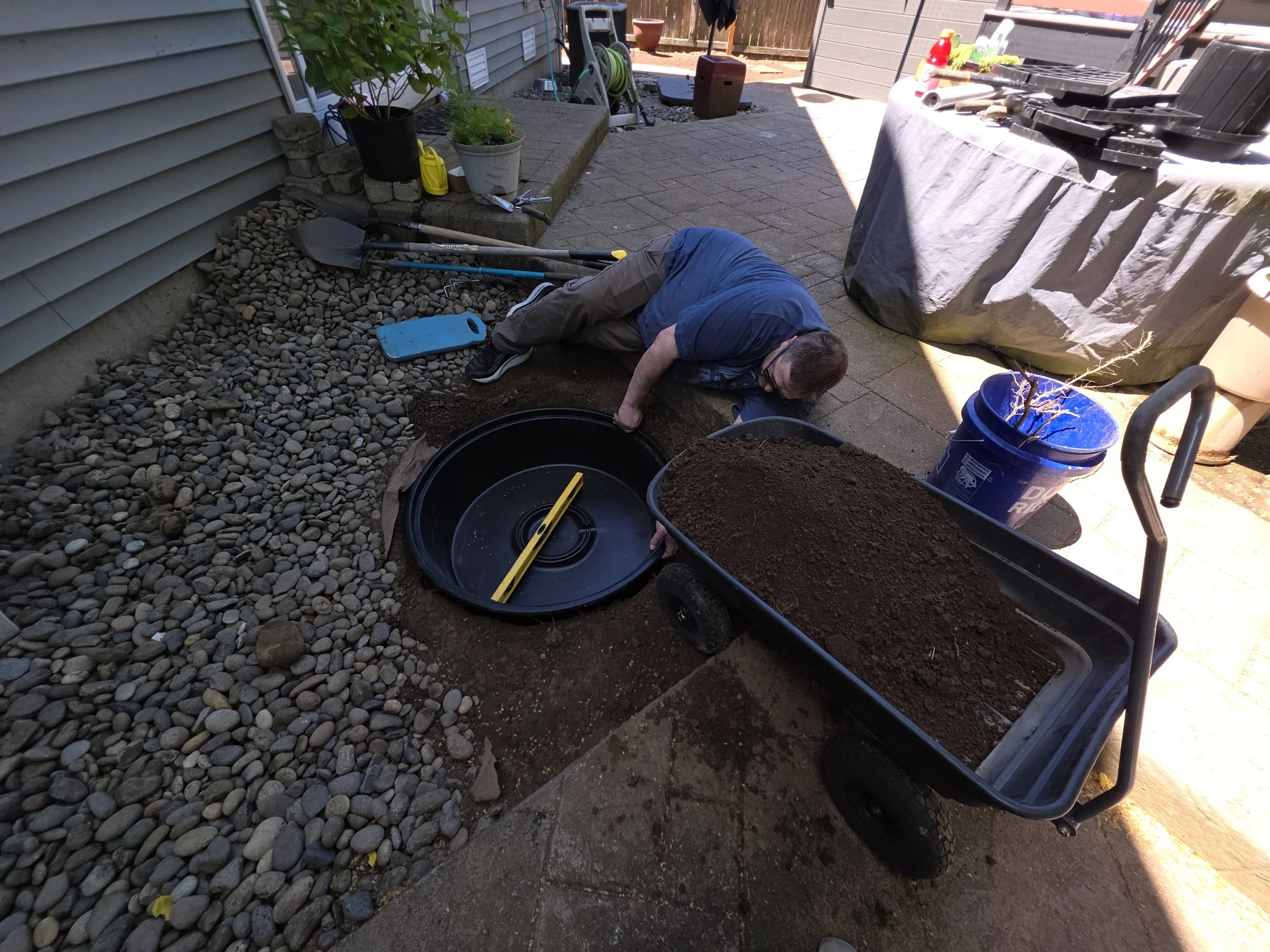 Kurt working in the yard with a yellow level in a black circular pond