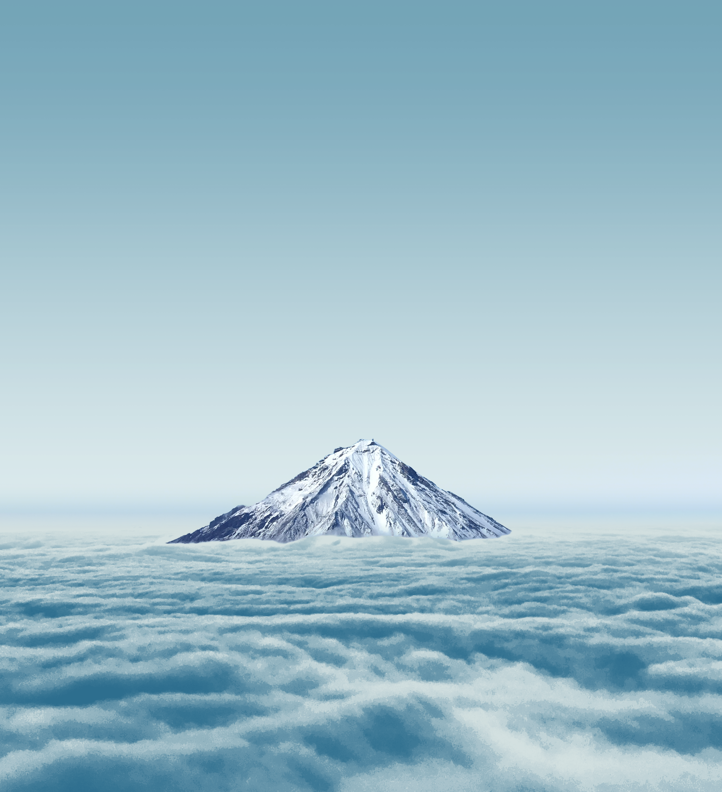 Snow-covered mountain rising above layers of cloud or fog with a clear sky above.