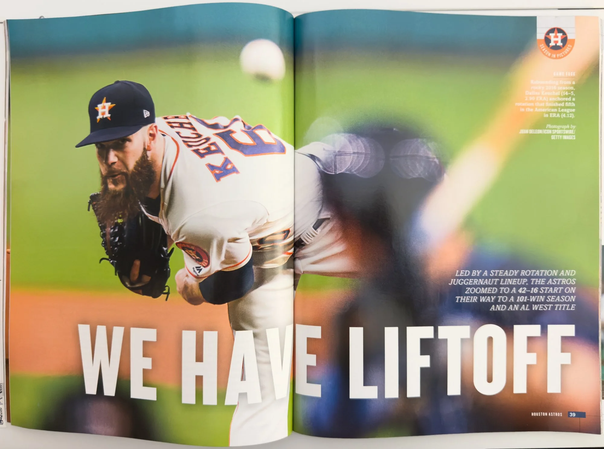 A baseball player from the Houston Astros, wearing a black cap with the team logo and a white jersey with orange and navy details, is in pitch during a game on the field with a blurred green background. The open magazine spread includes text about th