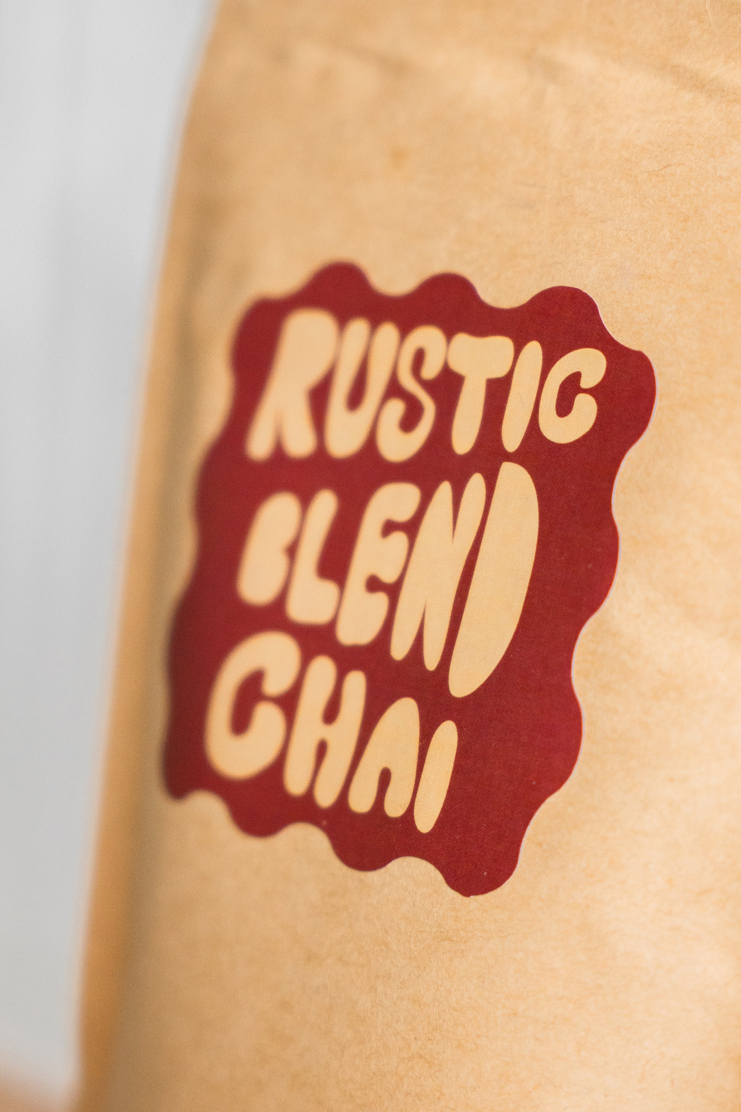 Close-up of a tan tattoo with red text that reads 'RUSTIC CLEAN CHICK' on light skin.