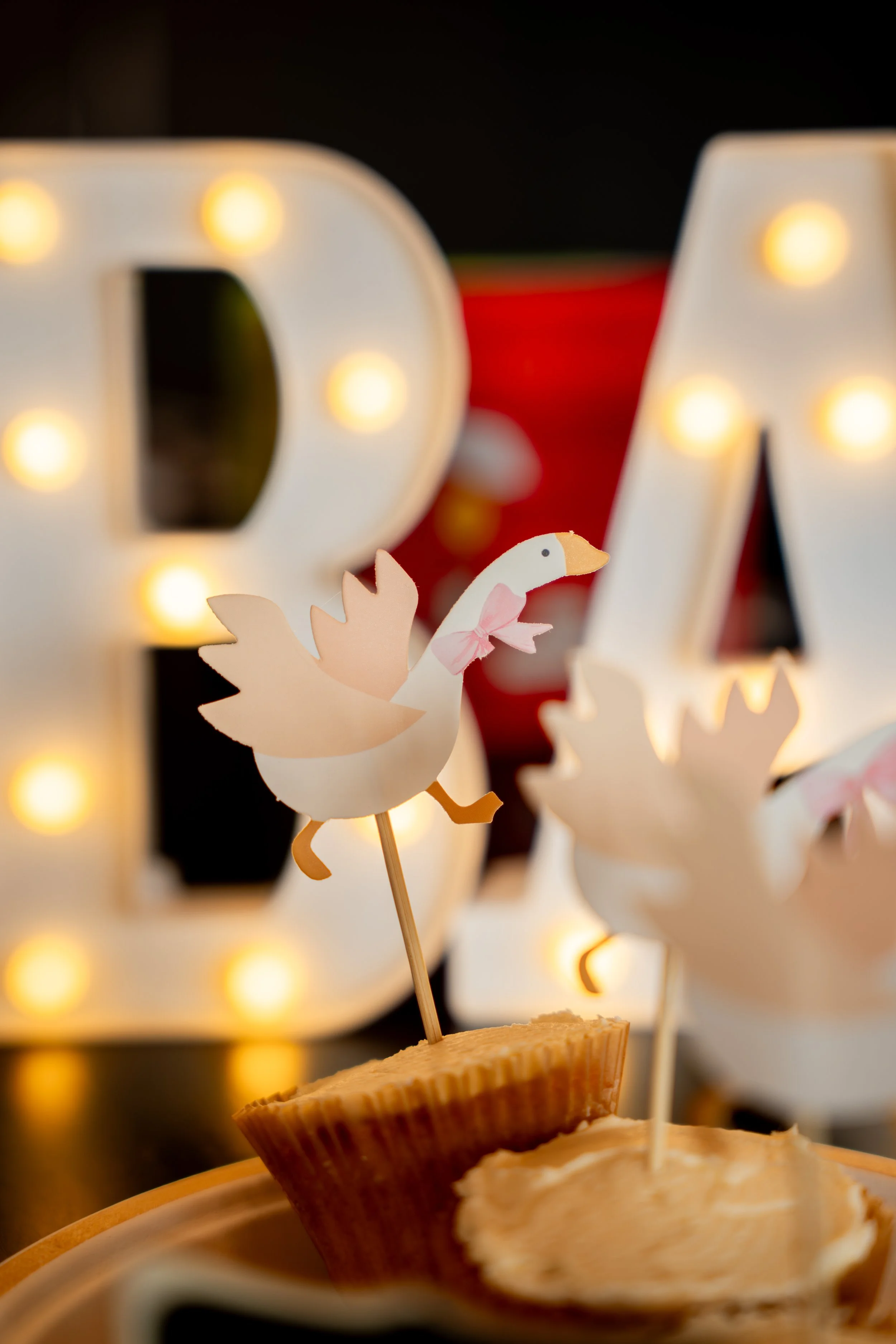 Close-up of decorative cardboard cutouts of a flying goose and a dragon, with large illuminated letters in the background.