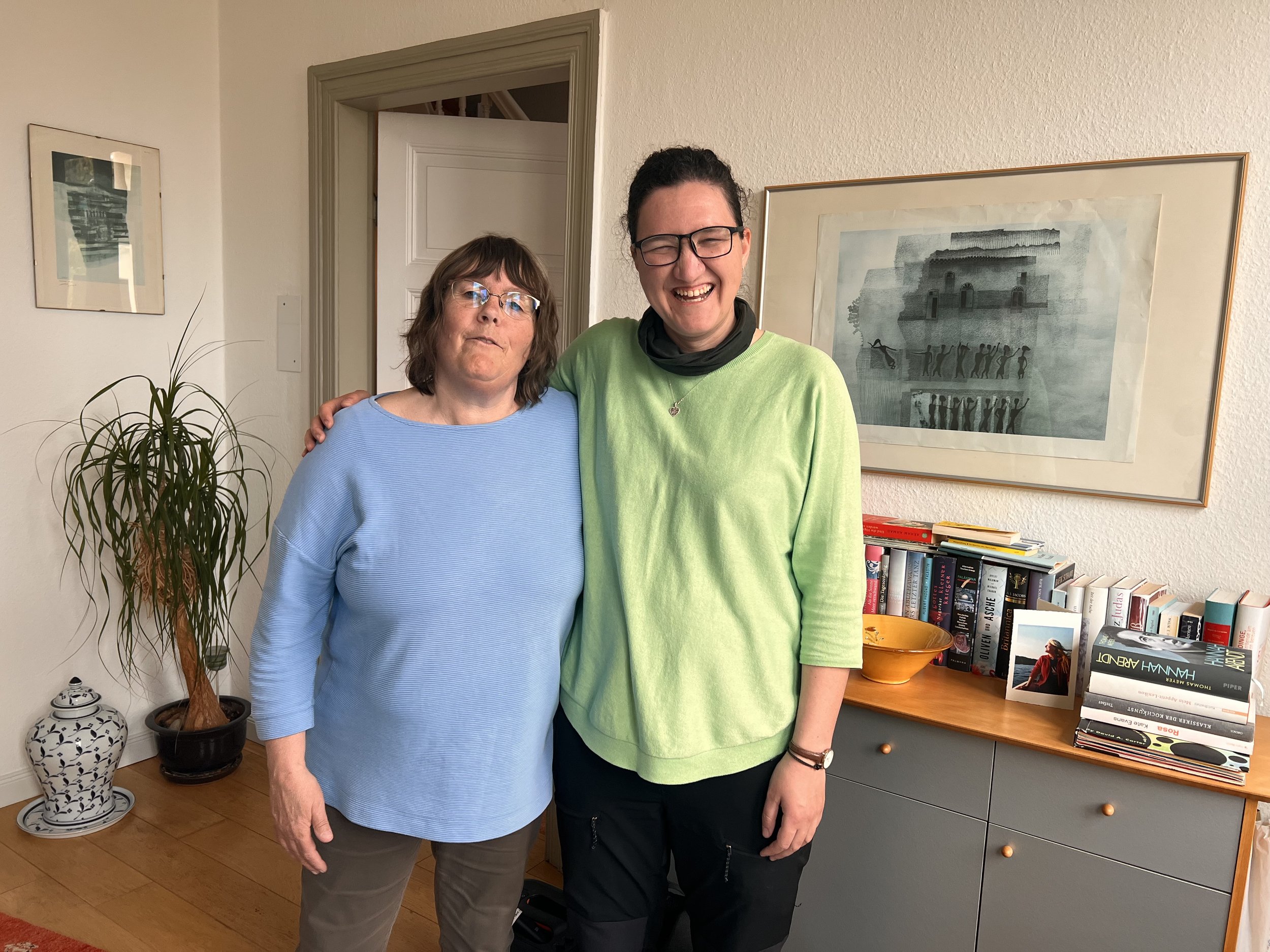 Vera and Anette standing together at Anette’s home, smiling in a comfortable and welcoming environment. The photograph captures a moment of friendship, hospitality, and personal connection.
