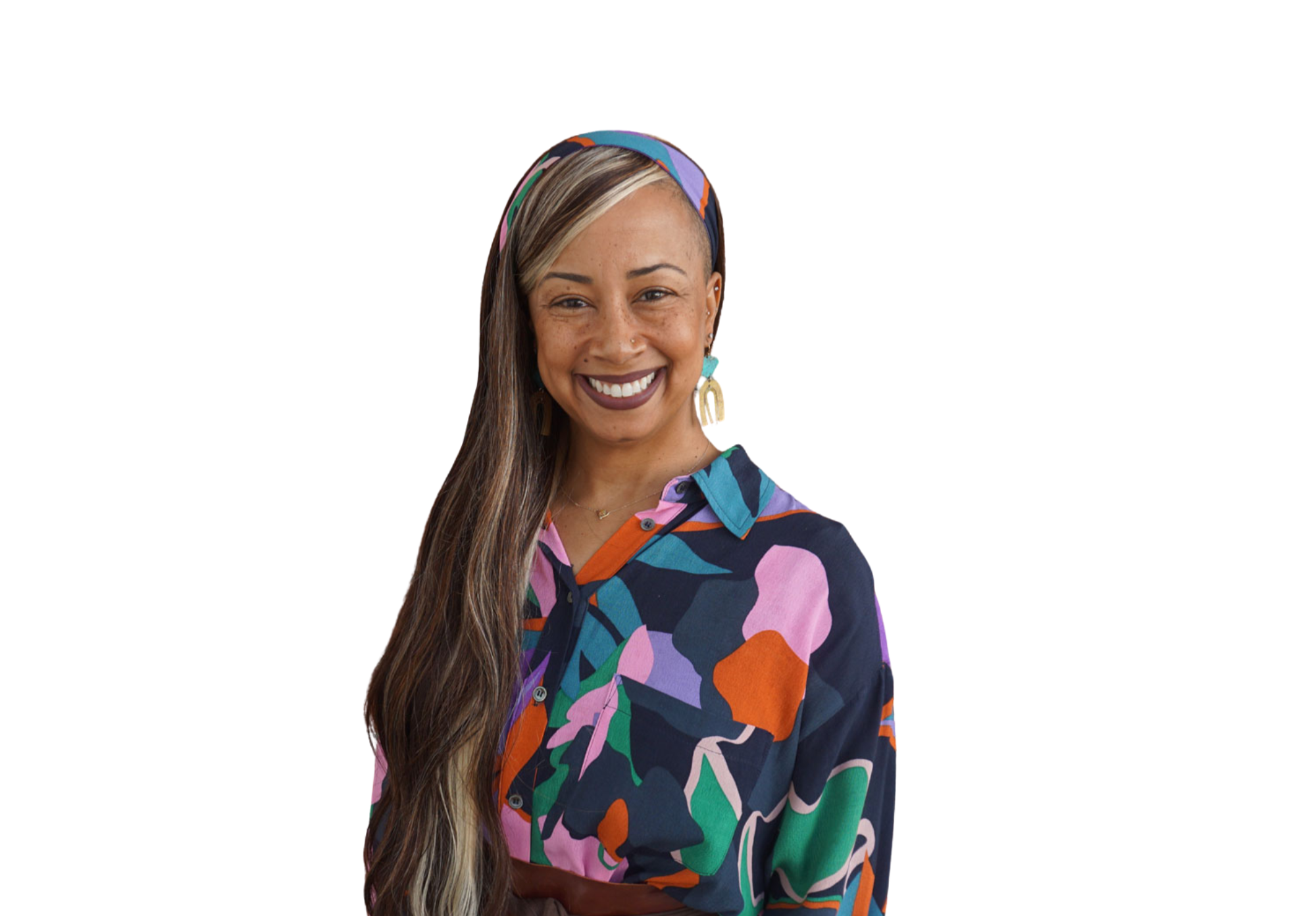A woman with long hair, wearing a colorful headscarf and a patterned shirt, smiling at the camera.