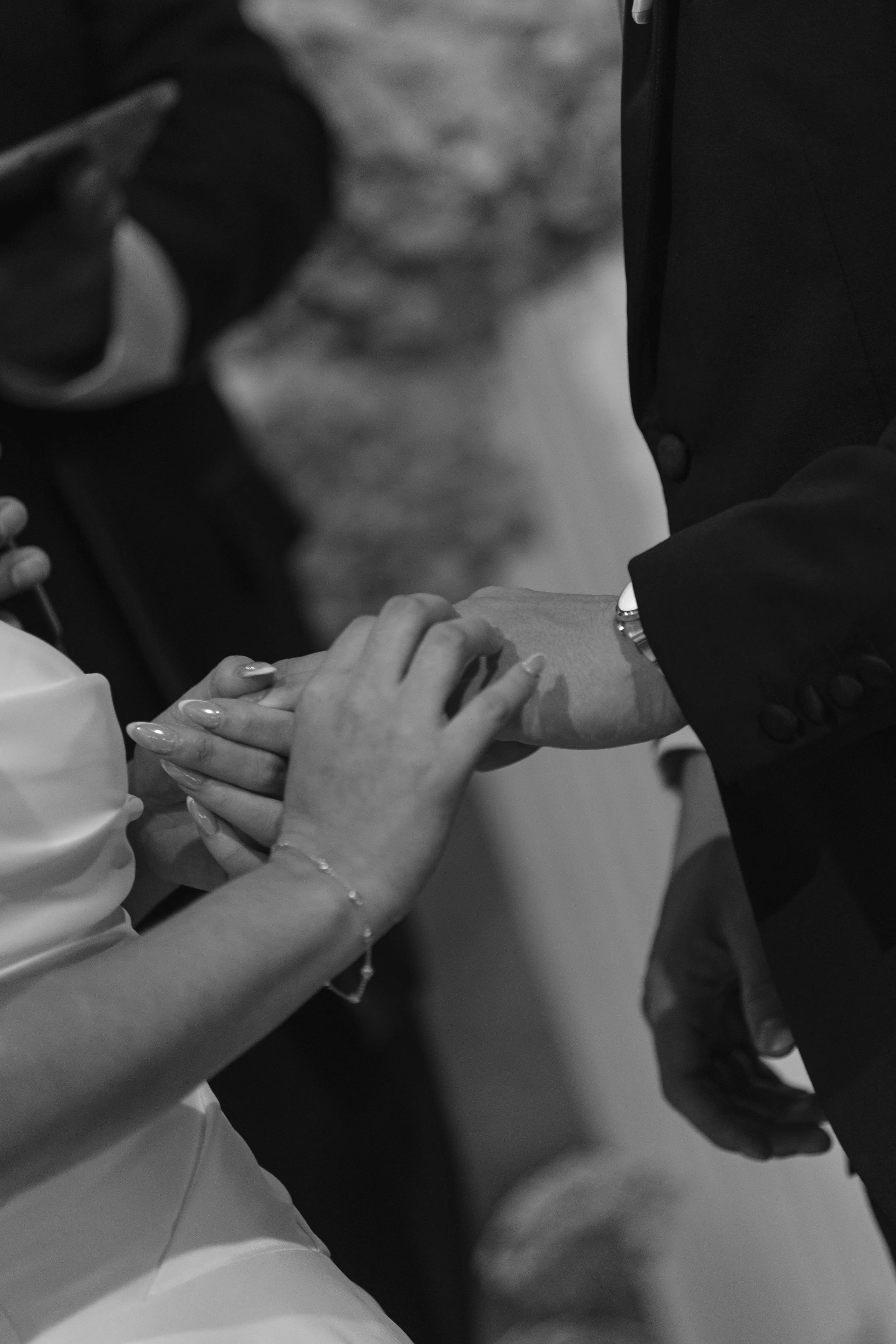 Close-up image of hands holding a pregnancy test with the pregnant woman and another person's hand touching. People are dressed in formal attire, suggesting a special occasion.