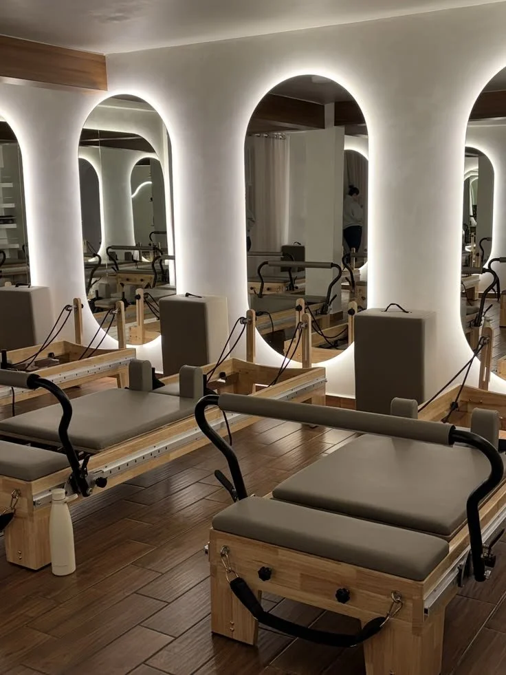 Salle de physiothérapie avec plusieurs tables de traitement et miroirs éclairés en arrière-plan.