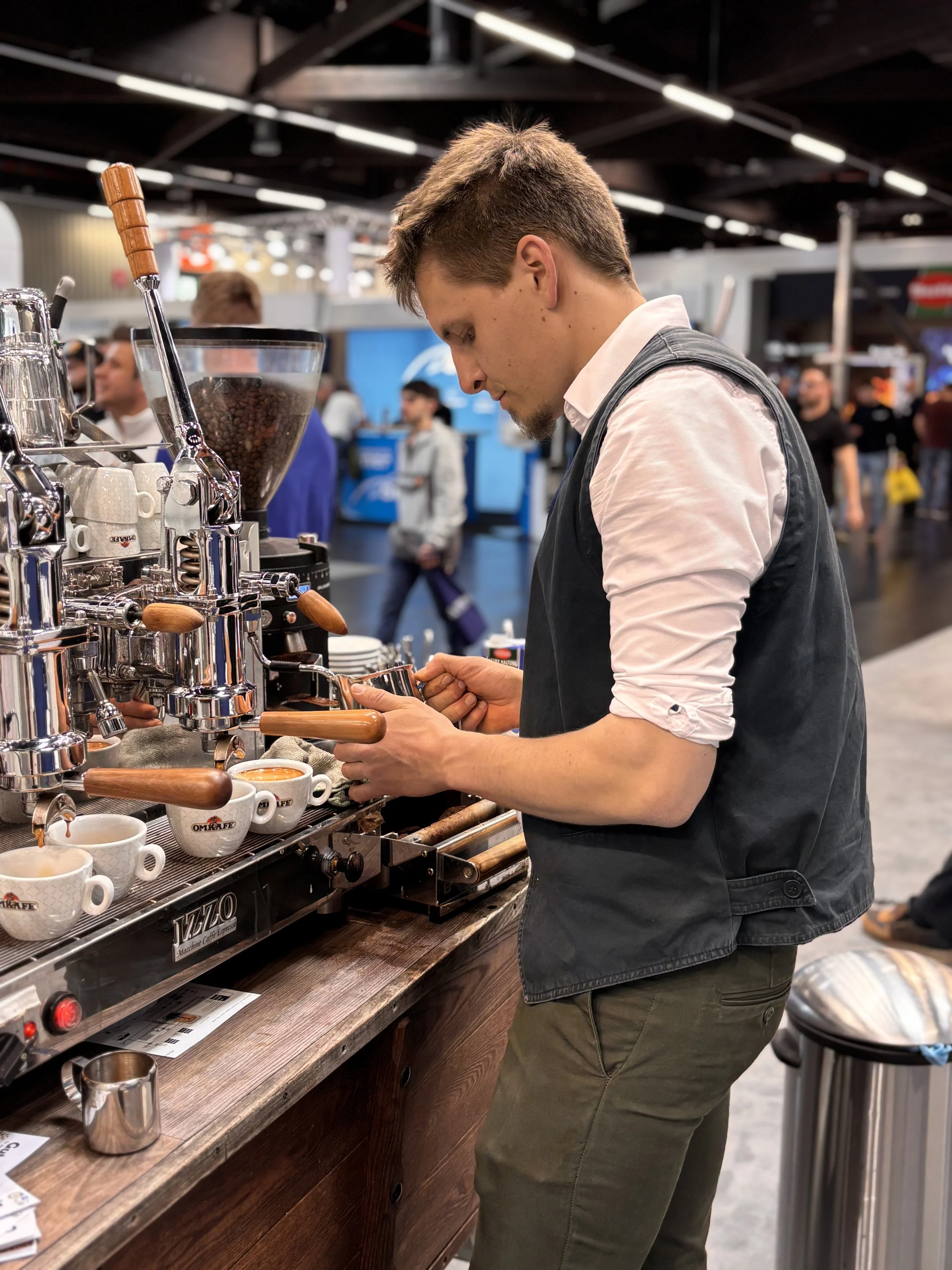 Junge Barista bereitet Kaffee in einer Espressomaschine zu in einem Café auf einer Messe.