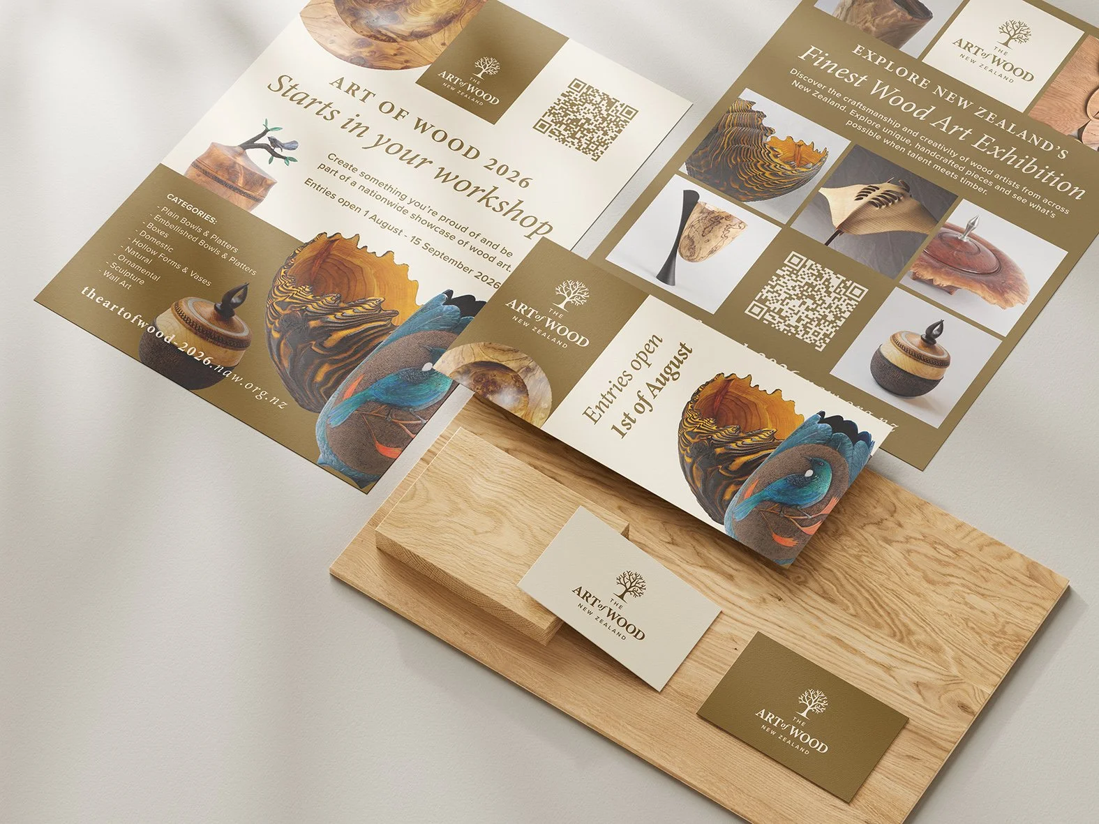 Flyers and business cards for The Art of the Wood New Zealand, promoting a wood art exhibition and workshop. The materials feature images of wooden art pieces, QR codes, and a logo with a tree, laid out on a wooden board.