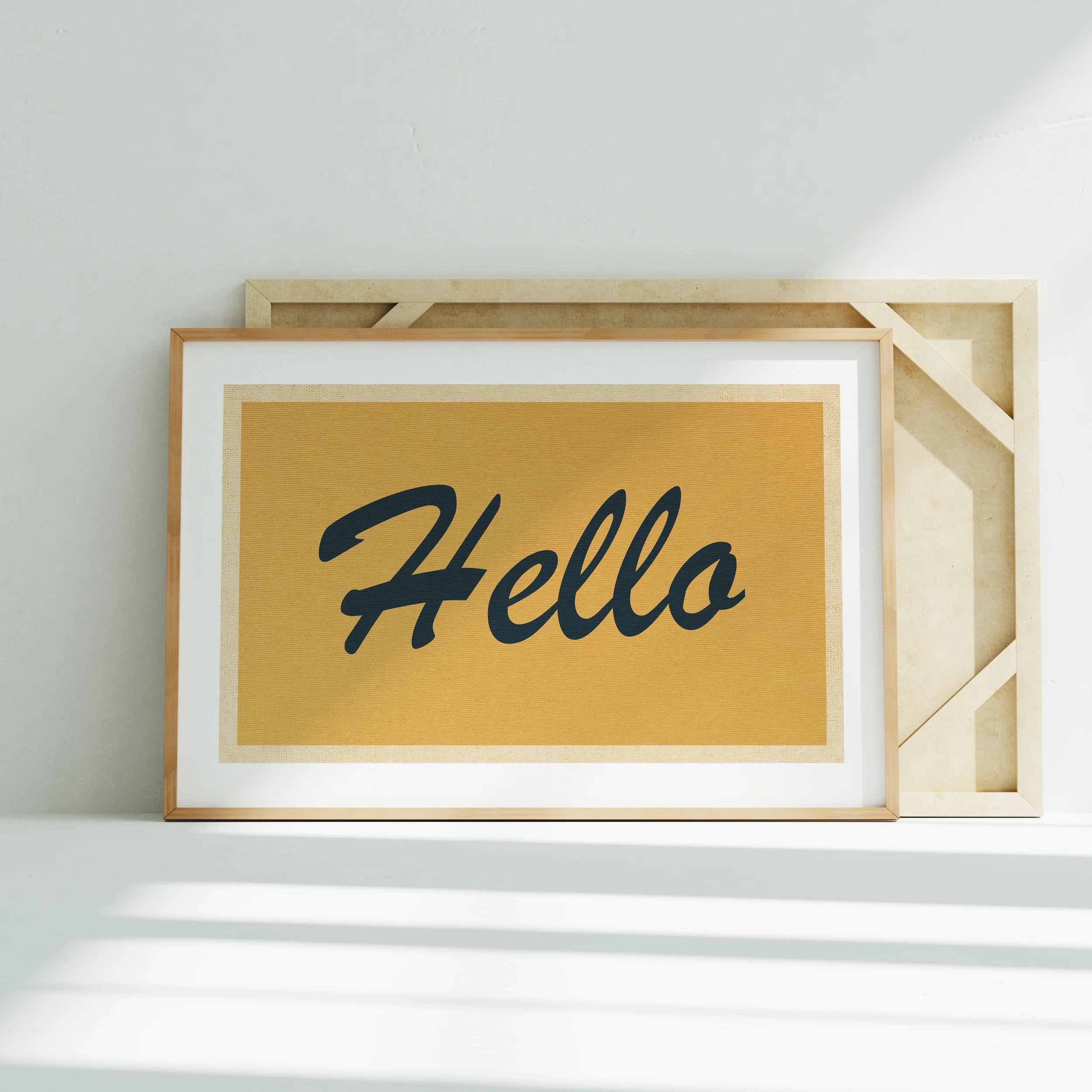 Close-up of a framed wall art piece with beige and black text, leaning against a white wall. The frame's top edge is visible. The background is plain and white.