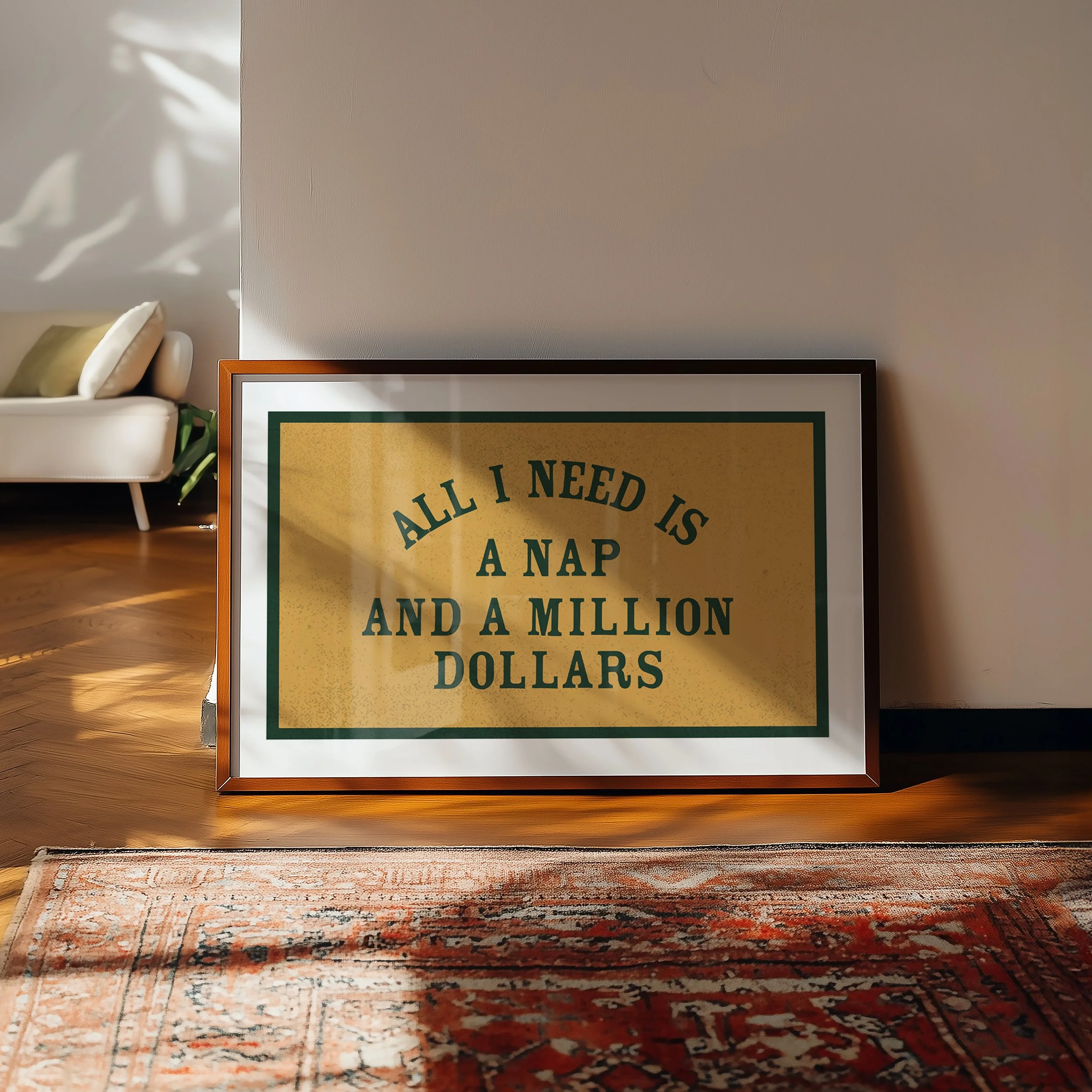 Part of an interior room with a wooden floor, a cream-colored rug, a beige chair with a green pillow, a basket with white and green objects, a framed poster on the floor reading "ALL I NEED IS A NAP AND A MILLION DOLLARS," a plain beige wall, and a side table with light-colored objects.