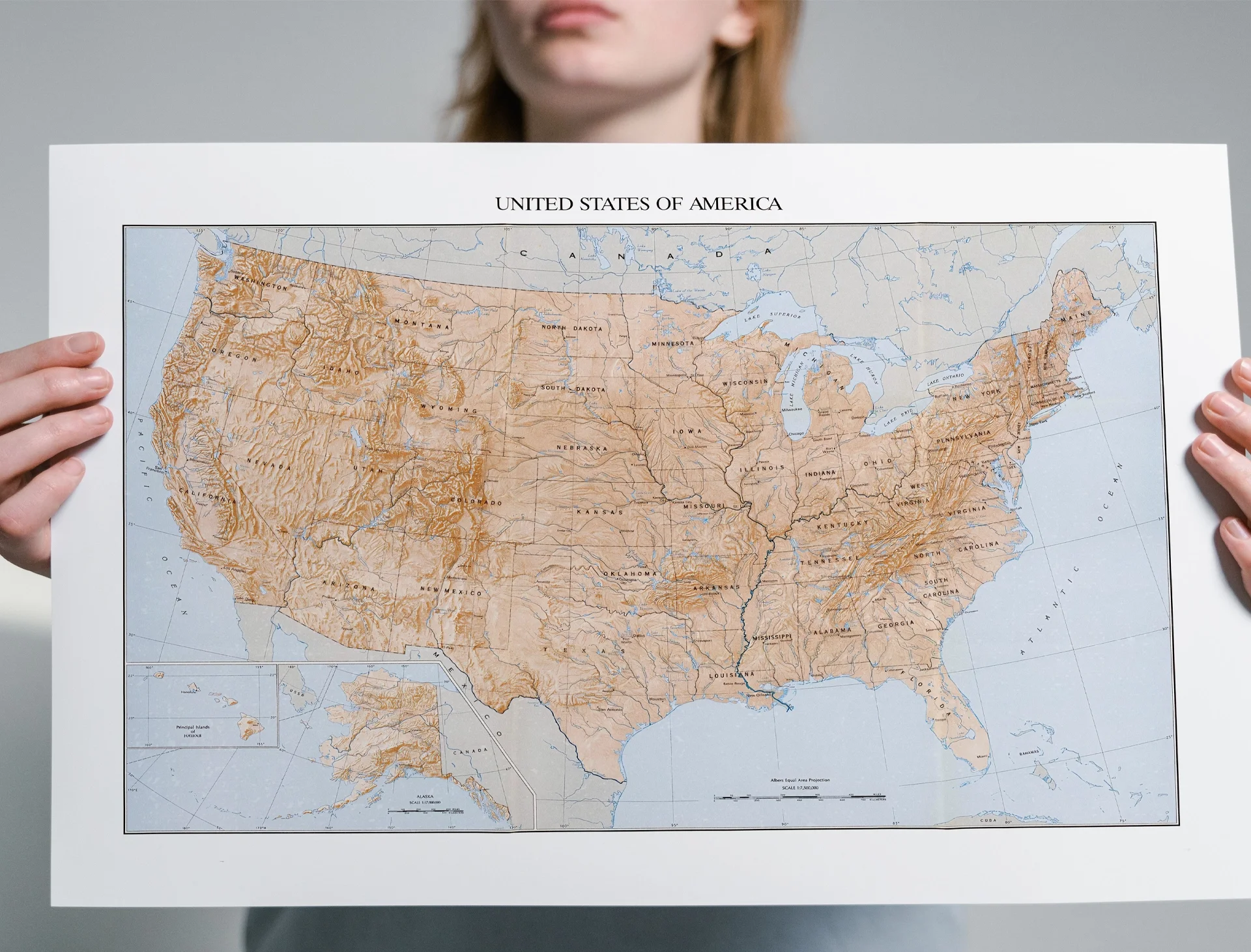 Person holding a detailed, vintage, physical map of the United States