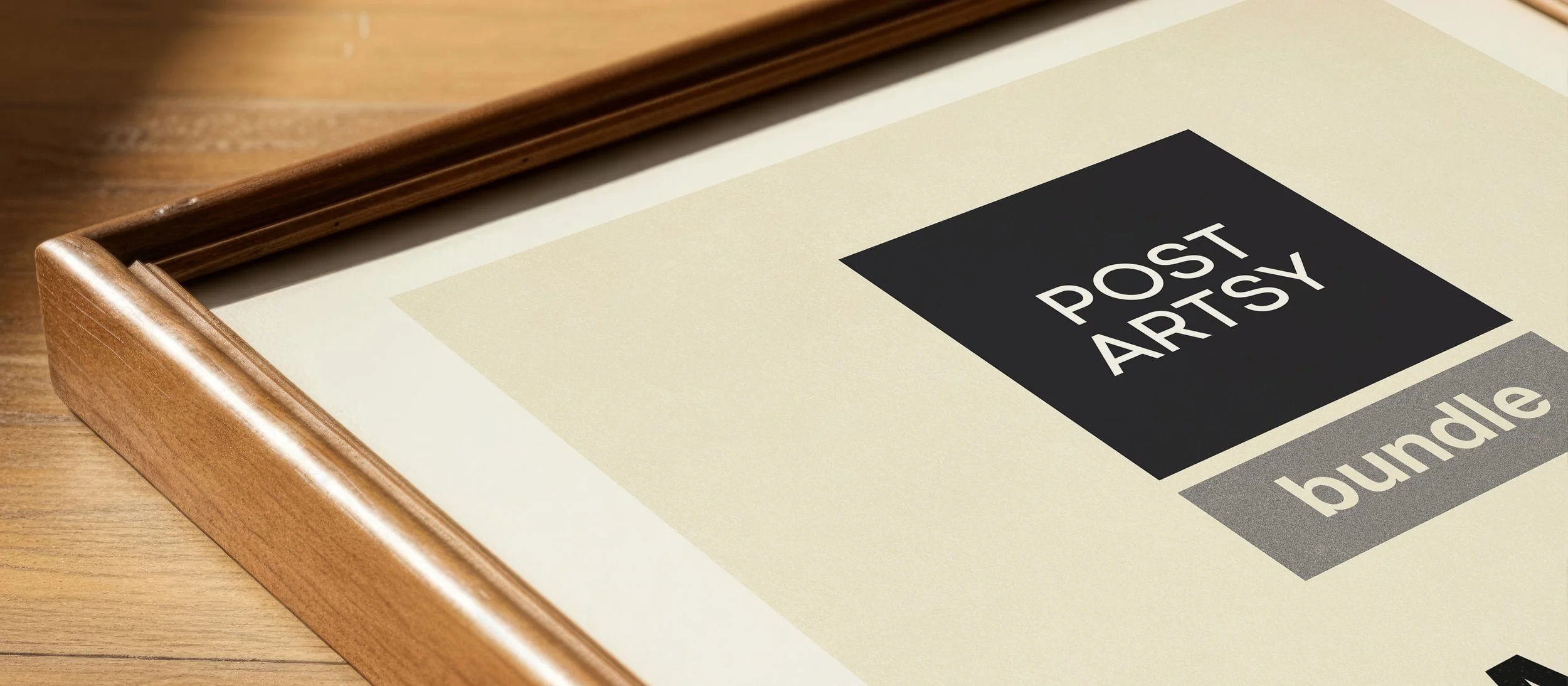 A framed print with the words 'PostArtsy' and 'bundle' on it, lying on a wooden surface.