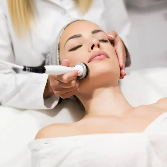 A woman receiving a facial treatment with a specialized device at a spa or clinic.