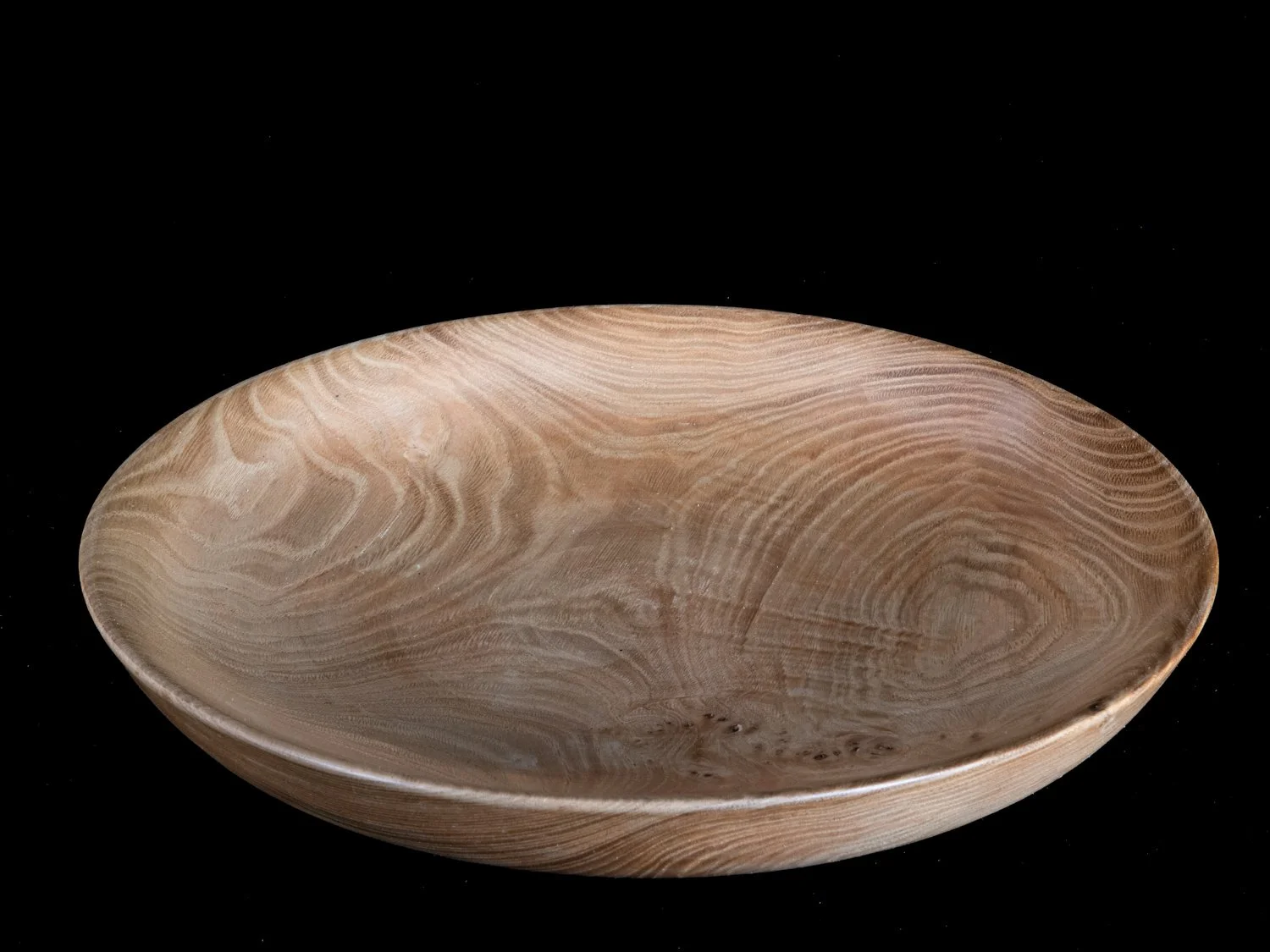A round wooden bowl with a natural wood grain pattern, placed against a black background.