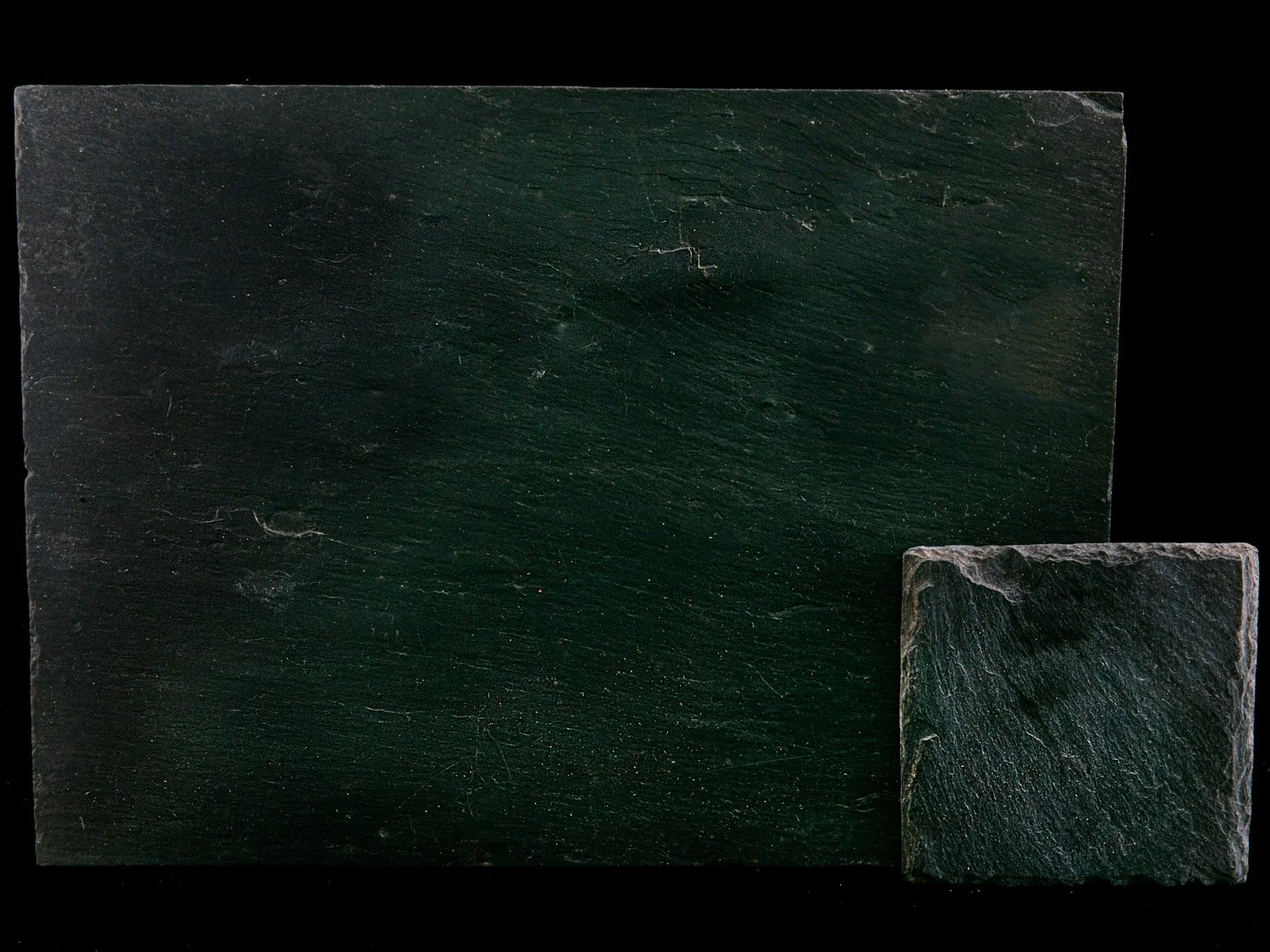 Two black slate tiles, one large and rectangular, one smaller and square, with a textured surface and natural grain visible.