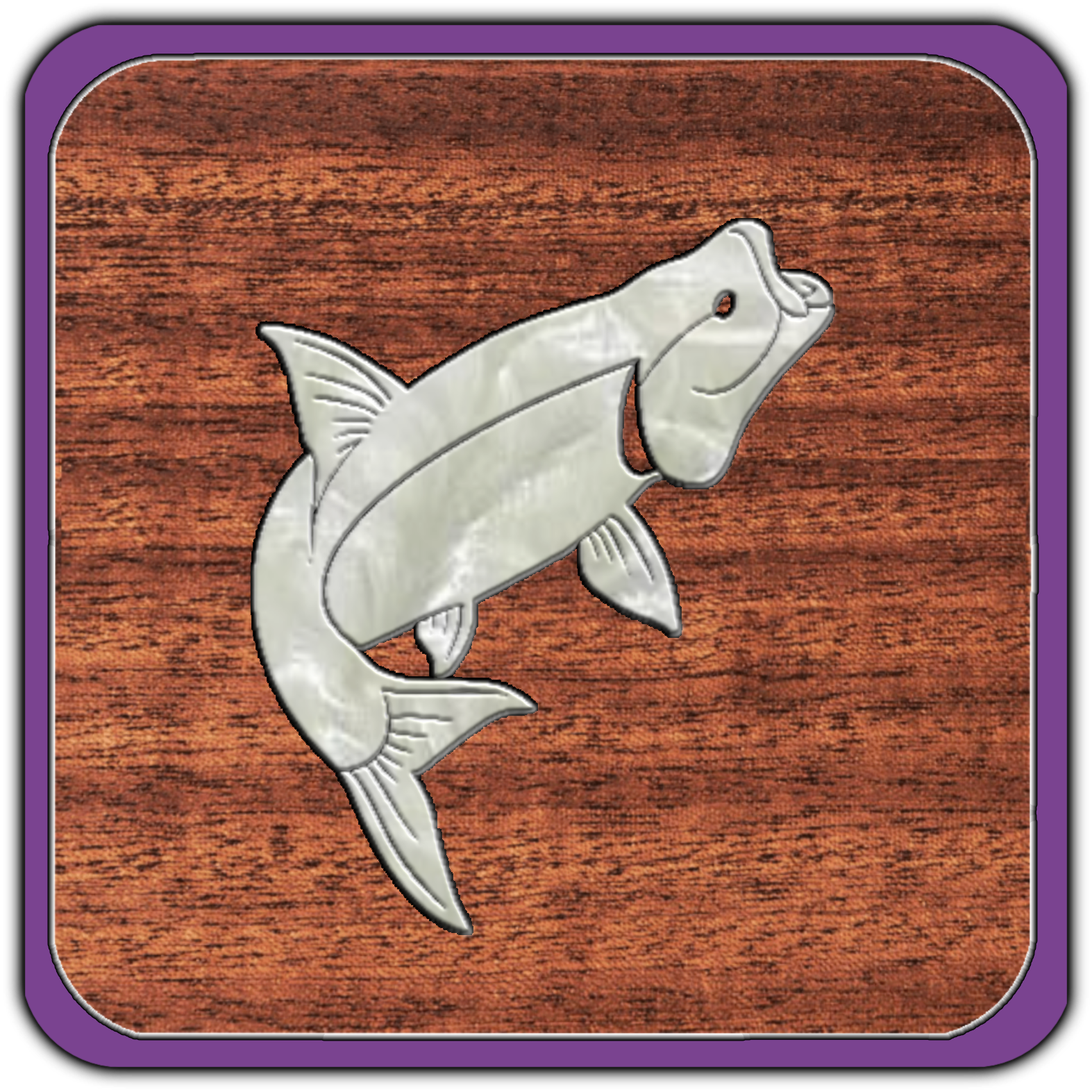 A metal fish-shaped keychain or ornament on a wooden surface with purple borders.