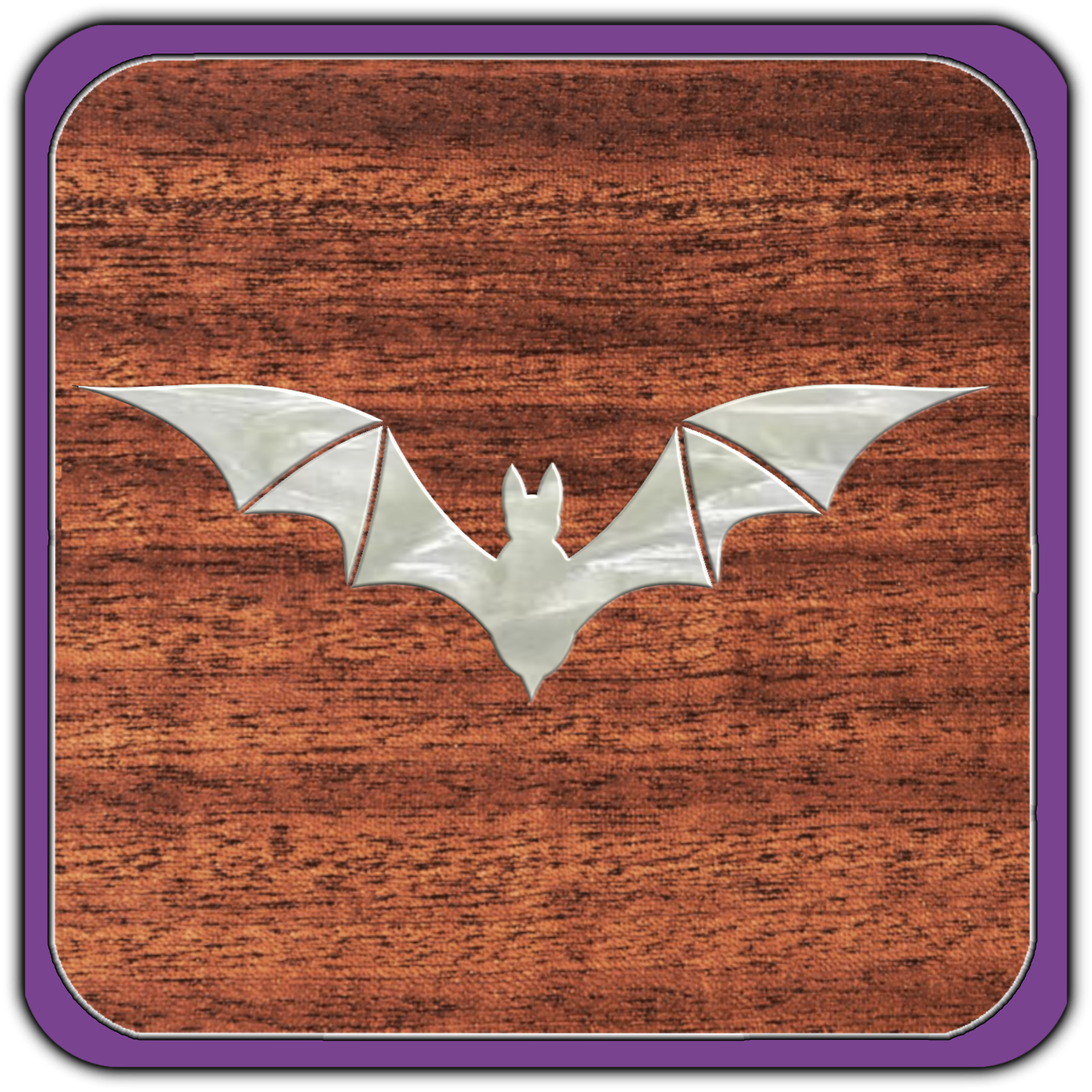 A metallic bat-shaped decoration on a wooden surface with purple border.