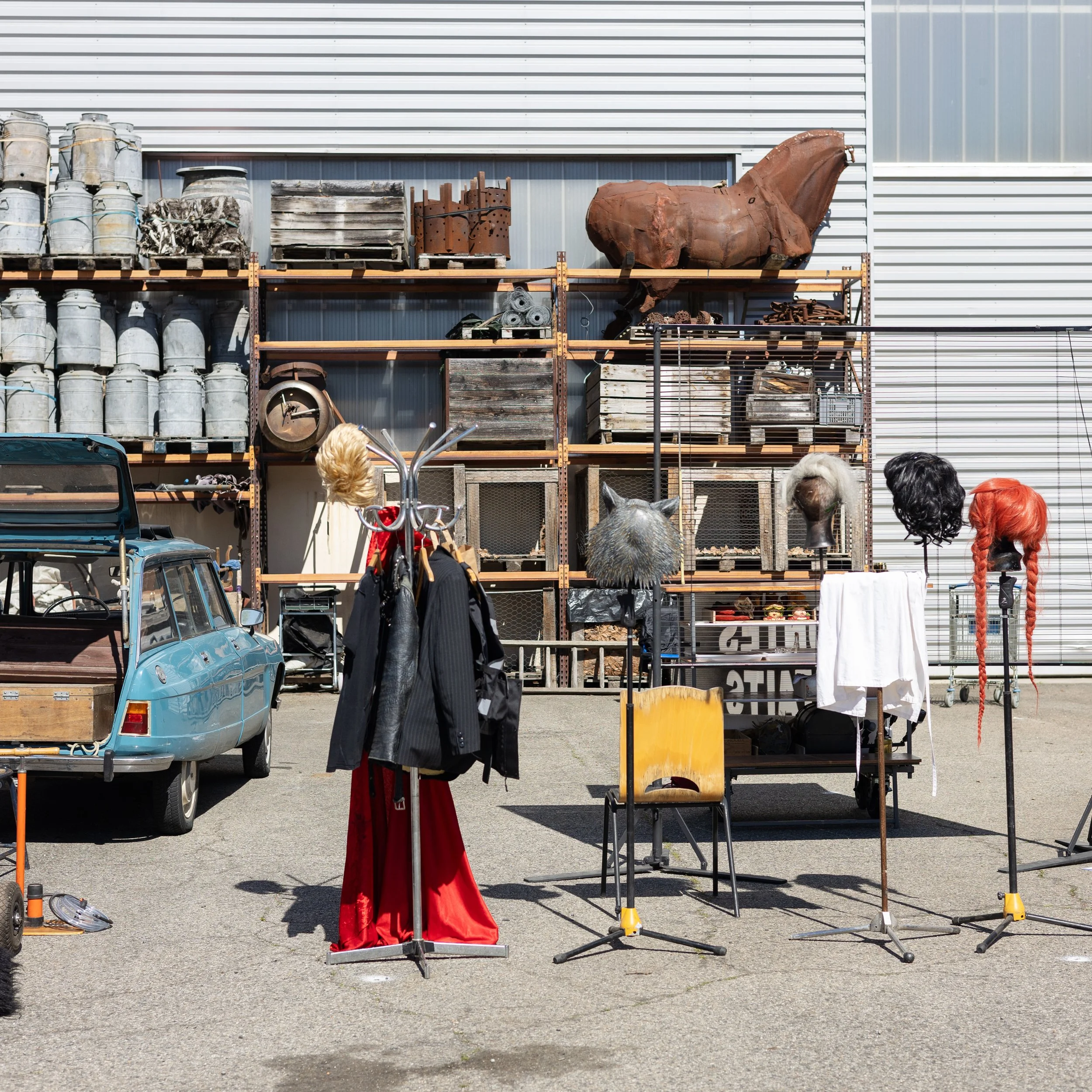 Stand avec des objets vintage et des bustes de cheval en dehors d'un bâtiment en métal.