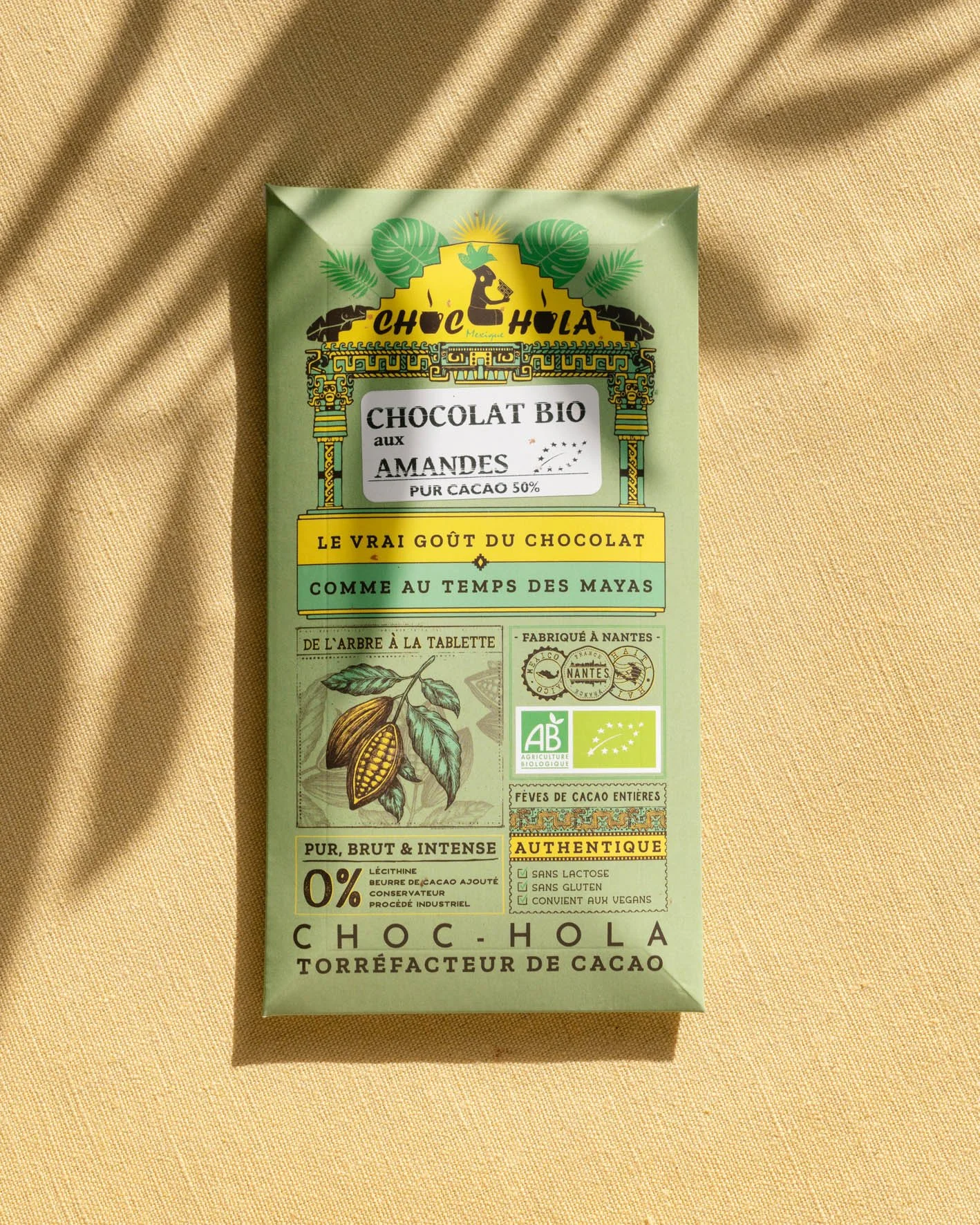 Paquet de chocolat biologique aux amandes avec des étiquettes en français et des symboles biologiques, posé sur un tissu beige.