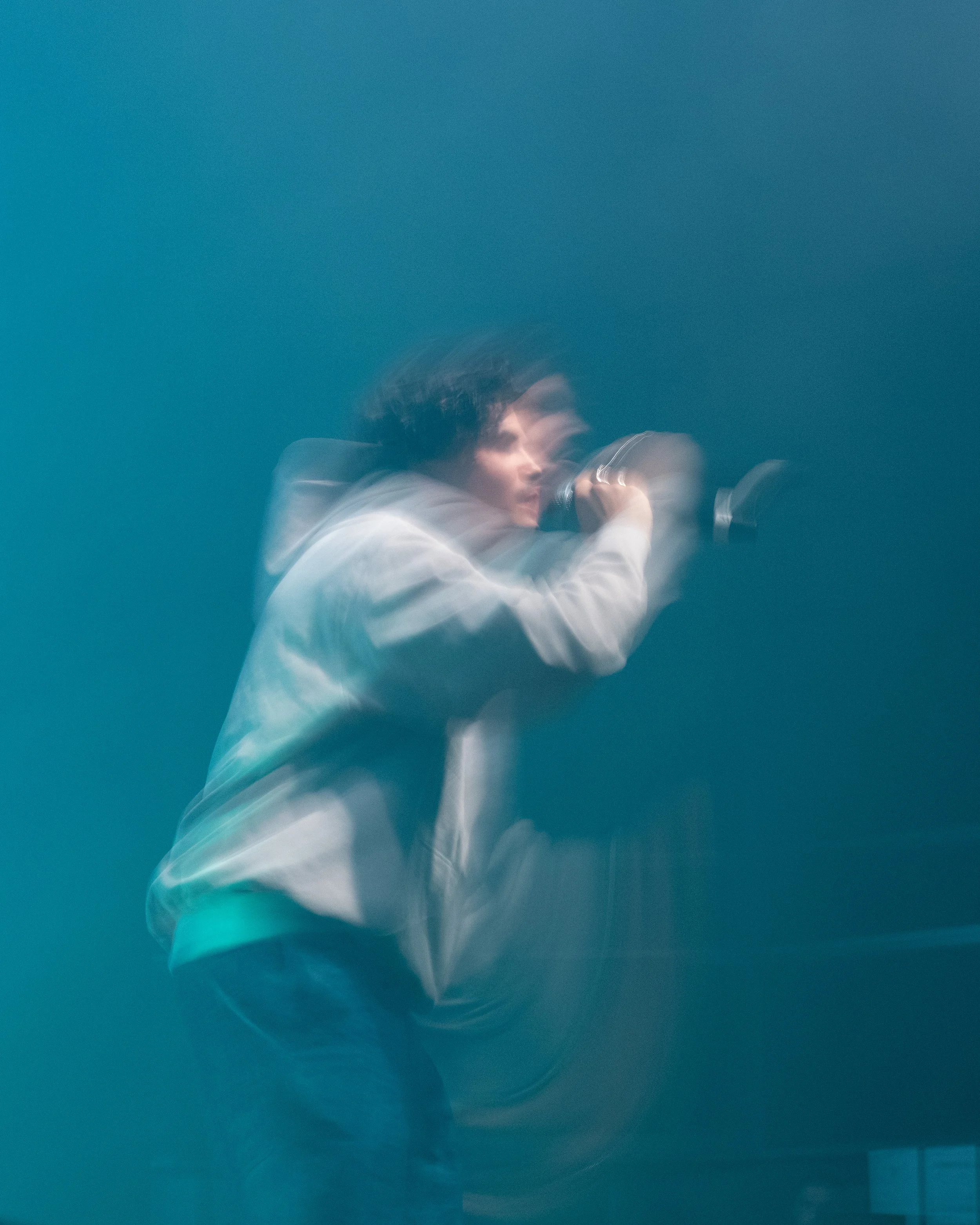 L'artiste Carbone chantant dans un microphone dans un décor flou avec une ambiance sombre et une lumière douce.