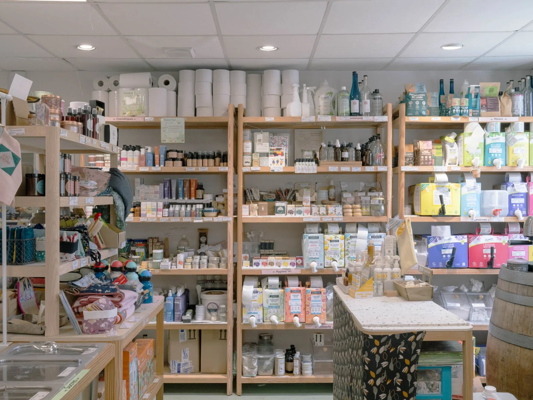 Rayonnages en bois remplis de produits de pharmacie et produits pour la maison dans une boutique.