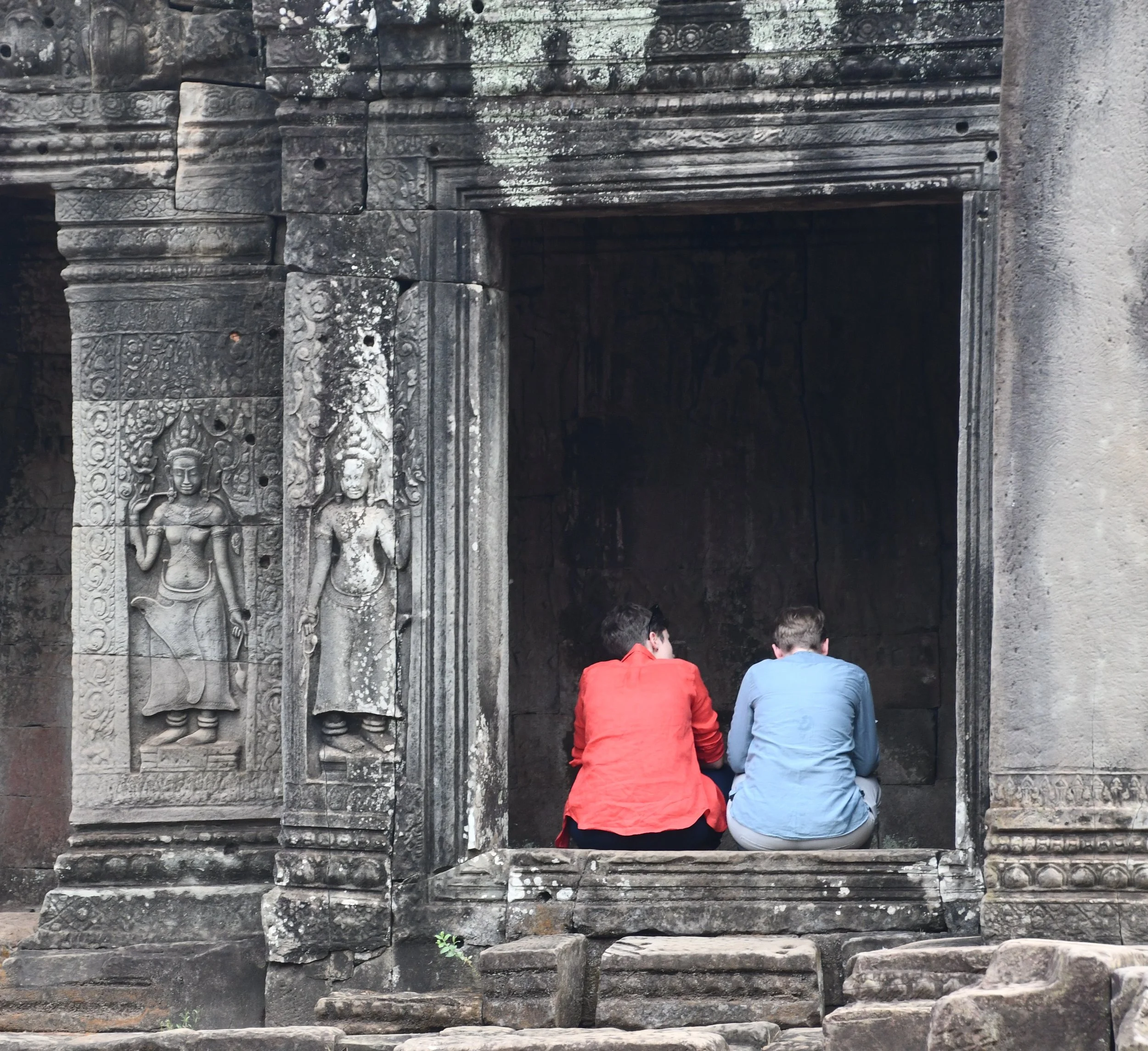 Contemplative photo by Gretchen Martens of two people sitting in a doorway at Angkor Wat in Cambodia