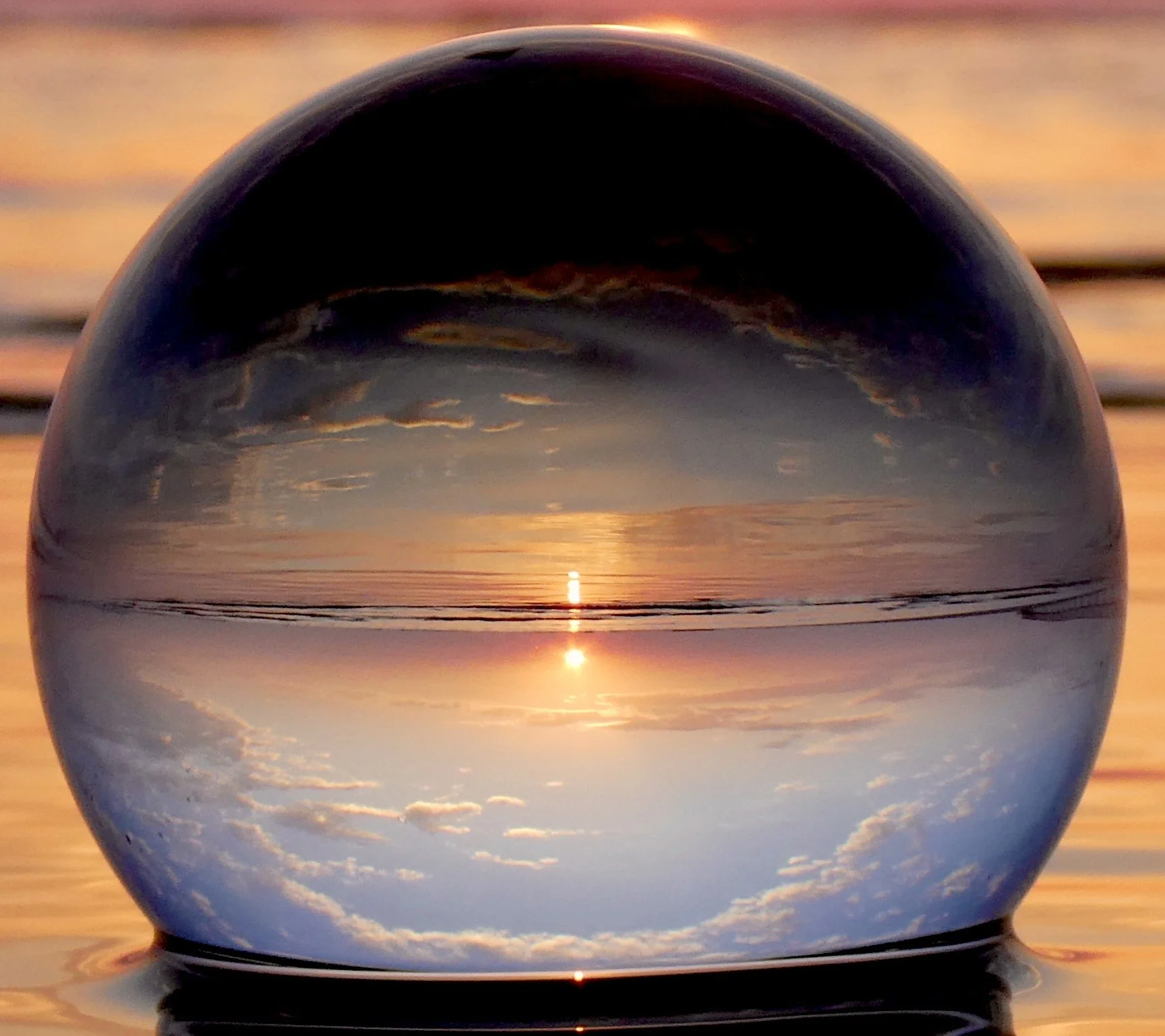 An image of an orb on a beach, the symbol for T The Glass Cradle™ which supports women at the edge of becoming