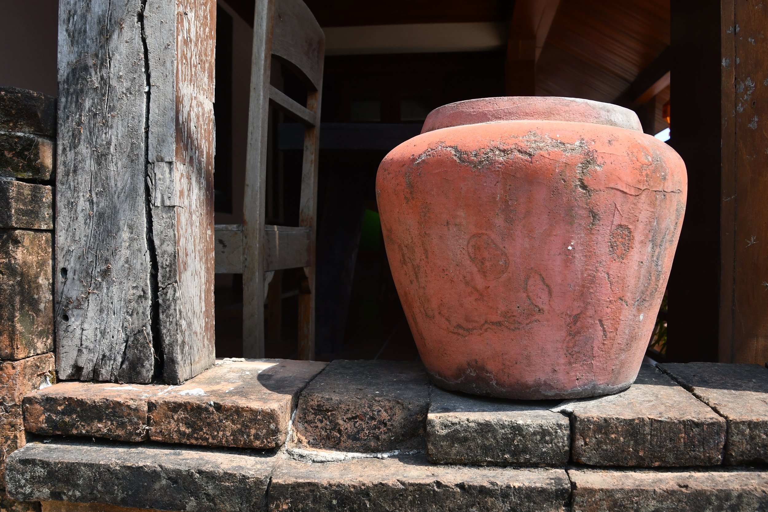 Photo by Gretchen Martens of tan old pot on a ledge in Thailand, speaking to stories as vessels for becoming, Red Tent Press, and its series Stories from the Threshold