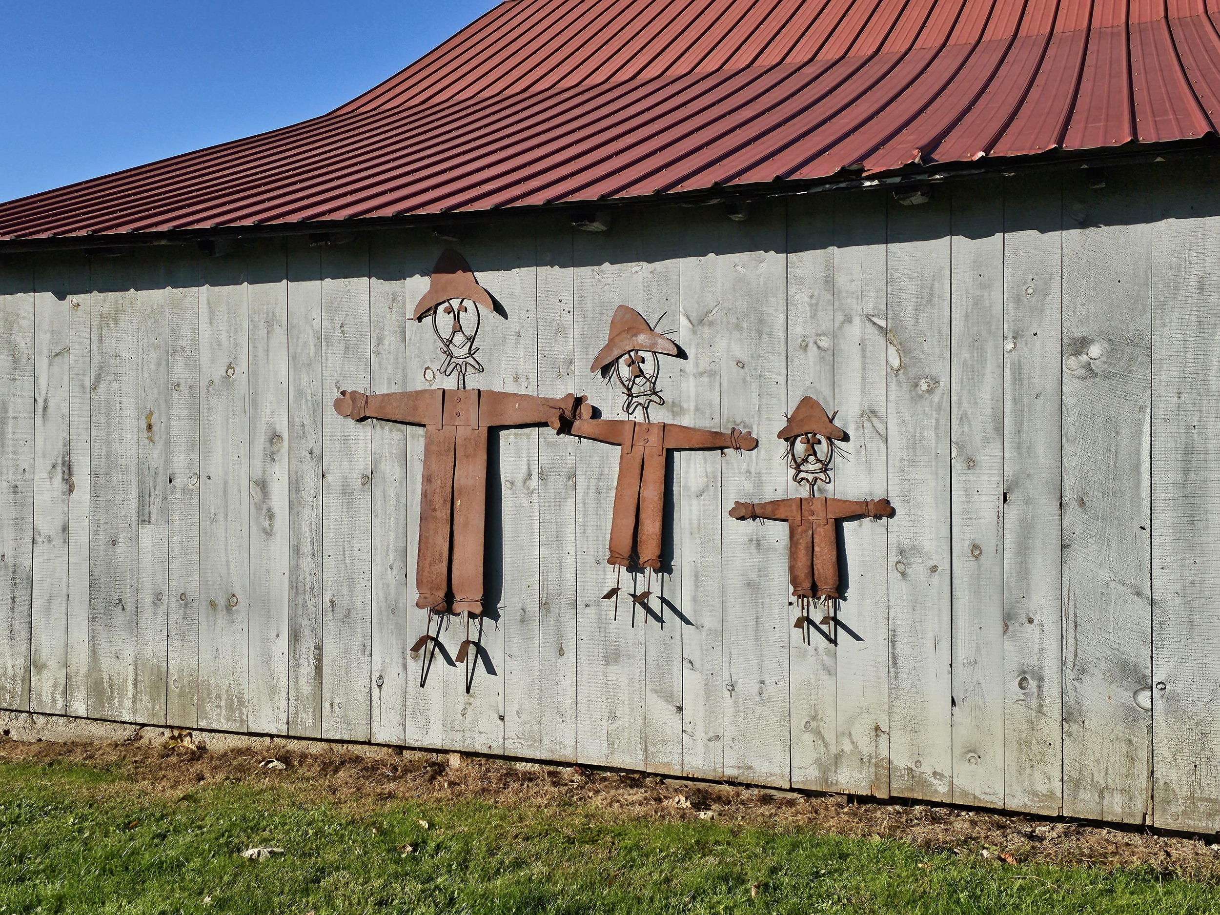 Photo by Gretchen Martens of the side of a barn in Pennsylvania with three whimsical metal figures