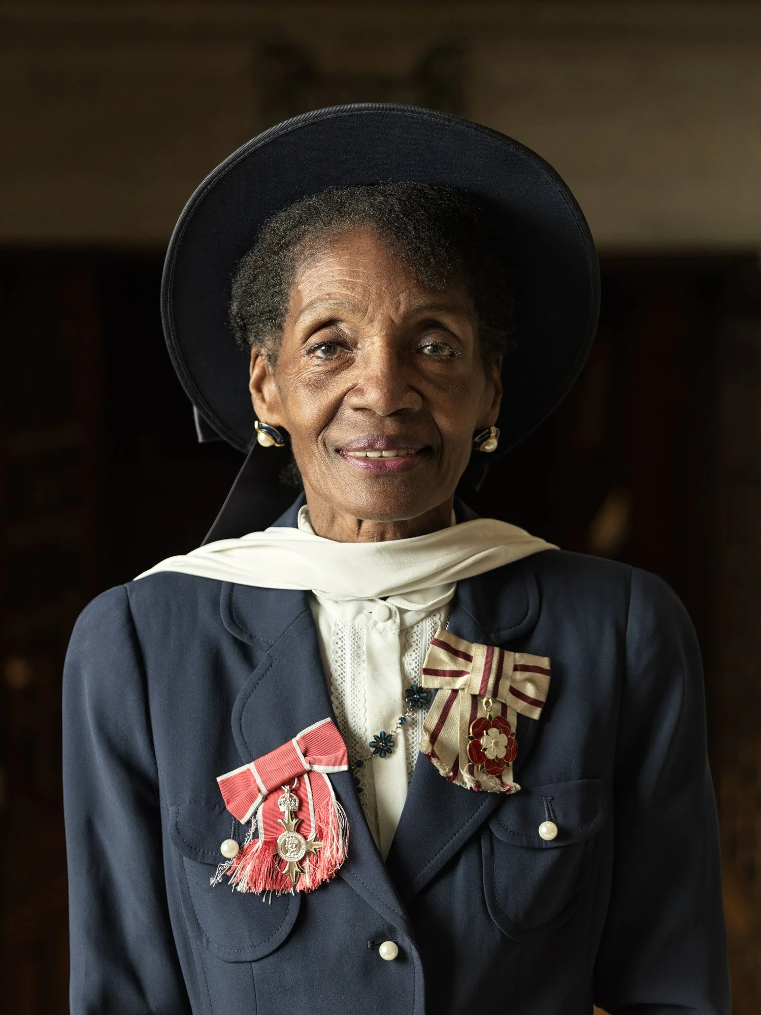 An elderly African American woman wearing a dark naval uniform with a large black hat, and adorned with multiple medals and ribbons.