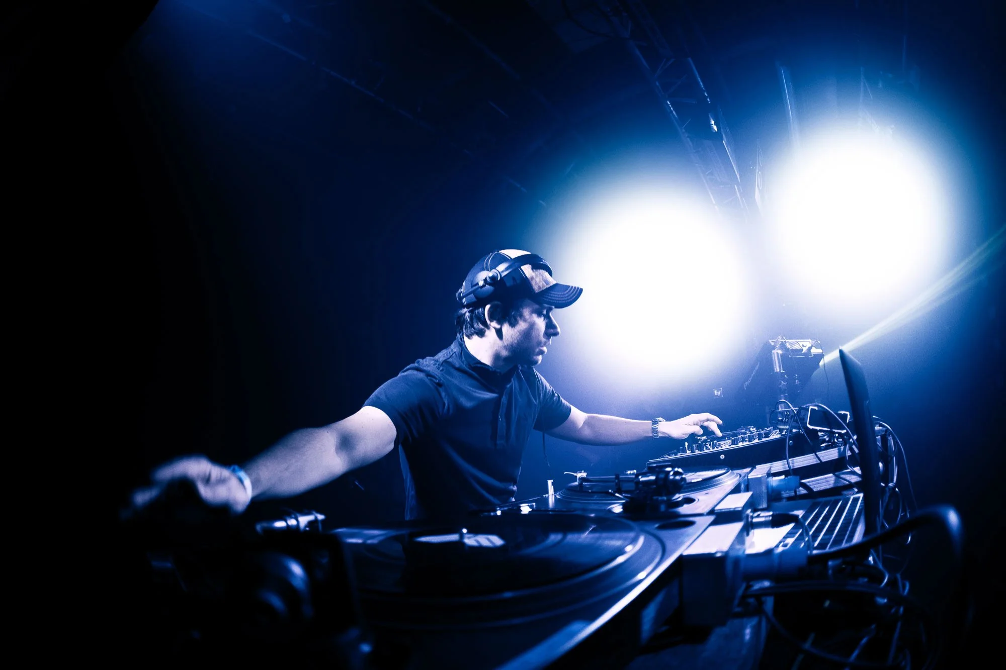 DJ Andy C, with bright stage lighting illuminating his face and equipment.
