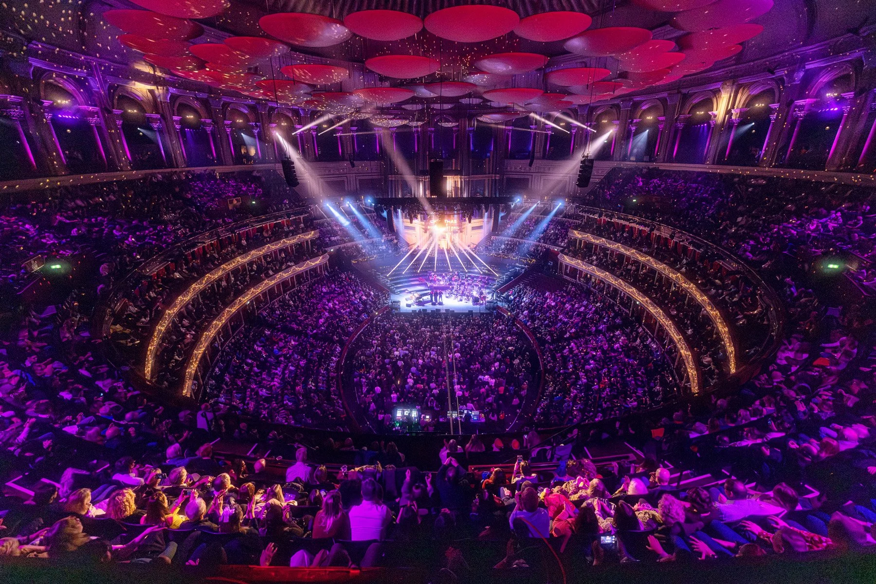 Royal Albert Hall  featuring Jamie Cullum, audience seated on multiple tiers, vibrant purple and gold lighting, and ceiling decorated with large pink and red circular fabric designs.